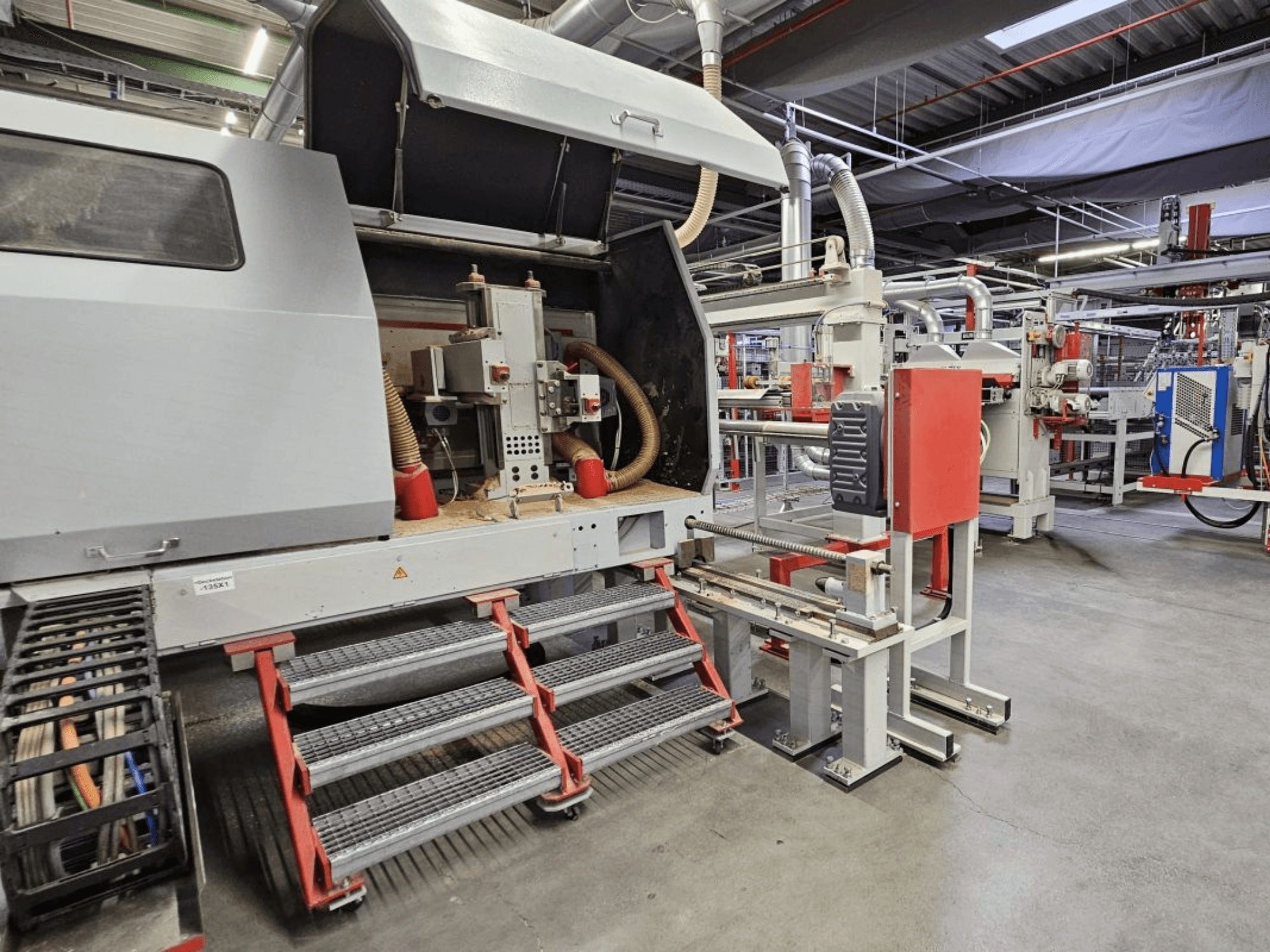 Vooraanzicht van de BURKLE Optima 1428/50 houtproductielijn, met treden en zichtbare machineonderdelen.