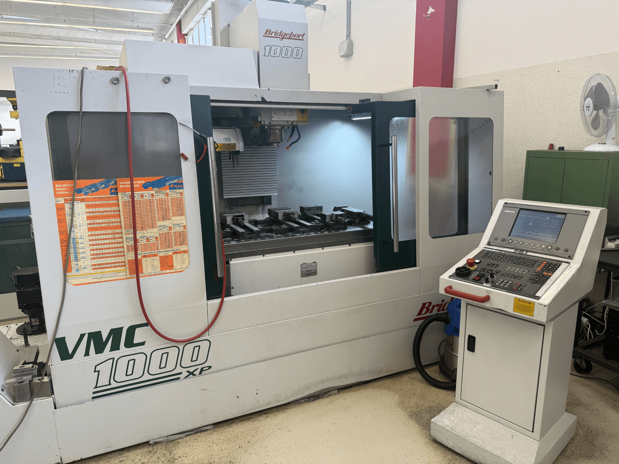 Vooraanzicht van het verticale bewerkingscentrum Bridgeport VMC 1000 XP, met daarin de bedieningselementen, het werkgebied en de gereedschapshouders.