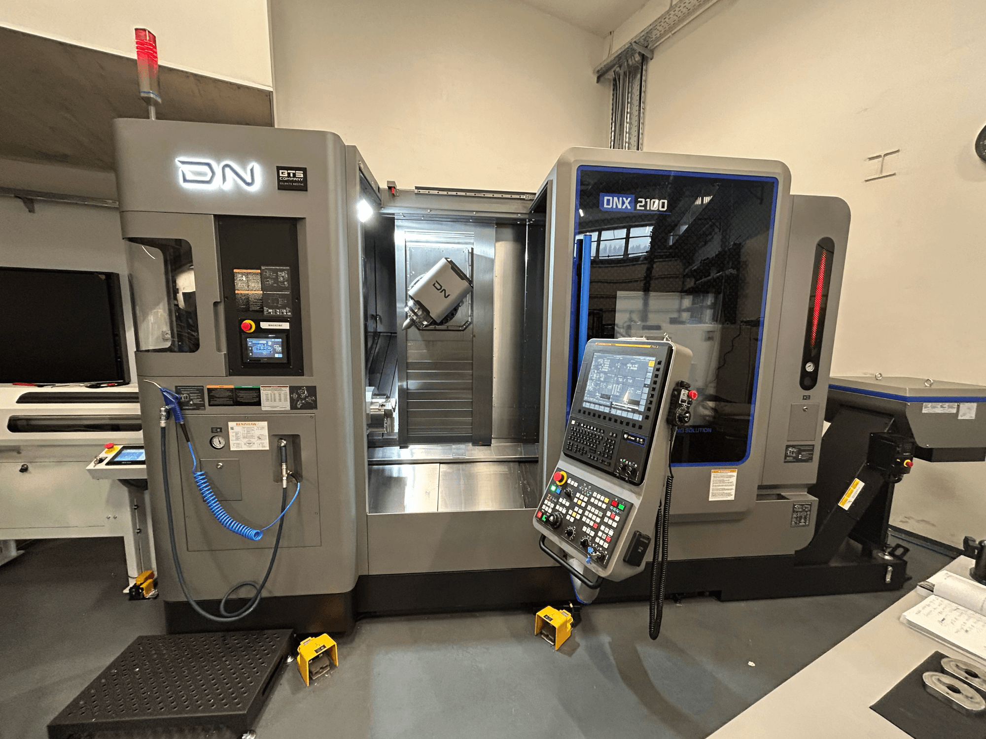 DN ONX 2100 CNC machine, vooraanzicht, met bedieningspaneel, werkgebied en gereedschap. Uitgerust met veiligheidsverlichting en bedrijfsindicatoren.