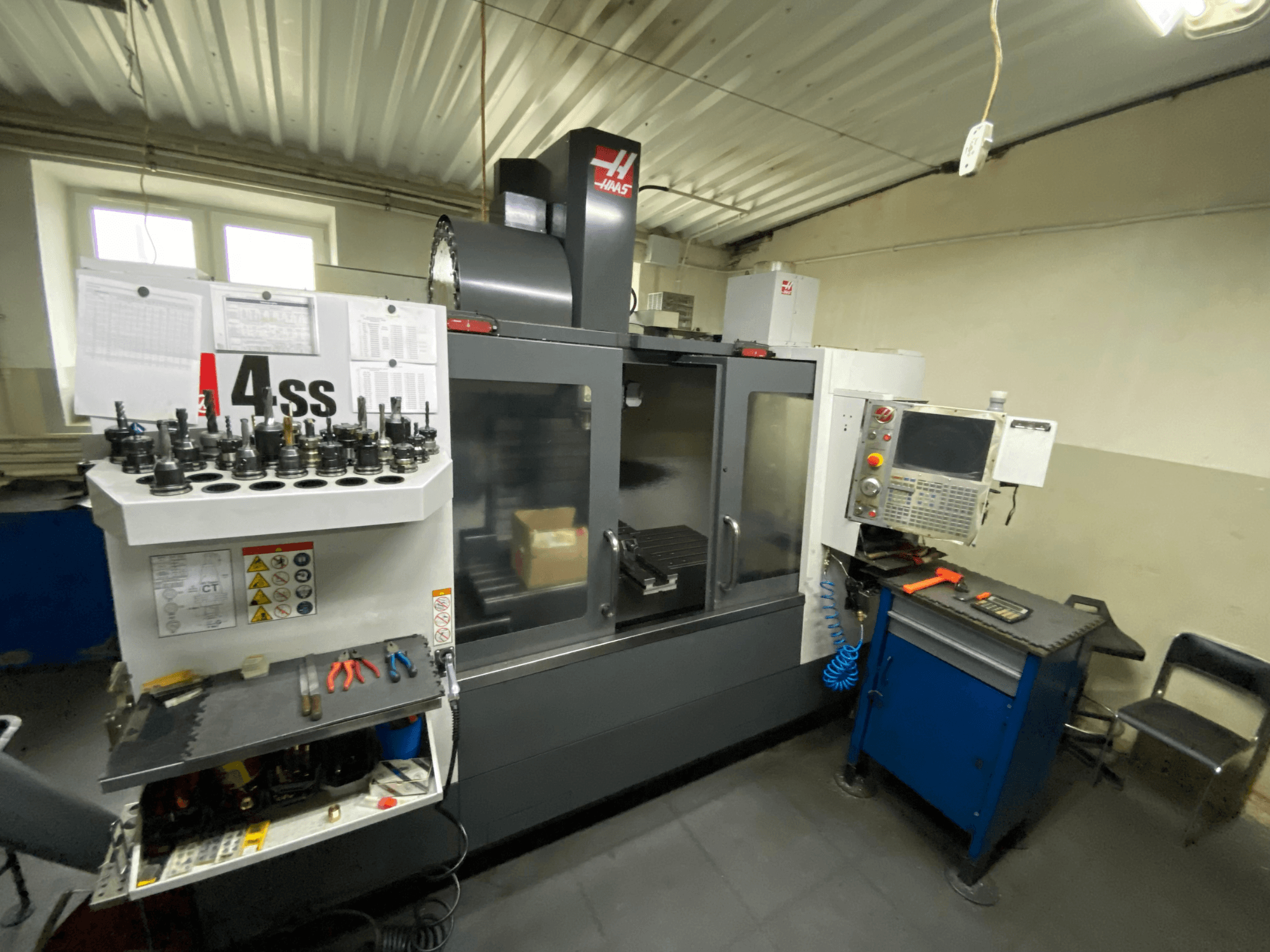 Haas VF-4SS verticaal bewerkingscentrum, vooraanzicht met gereedschapshouders en bedieningspaneel. De gebruikte gereedschappen en de werkruimte zijn zichtbaar.