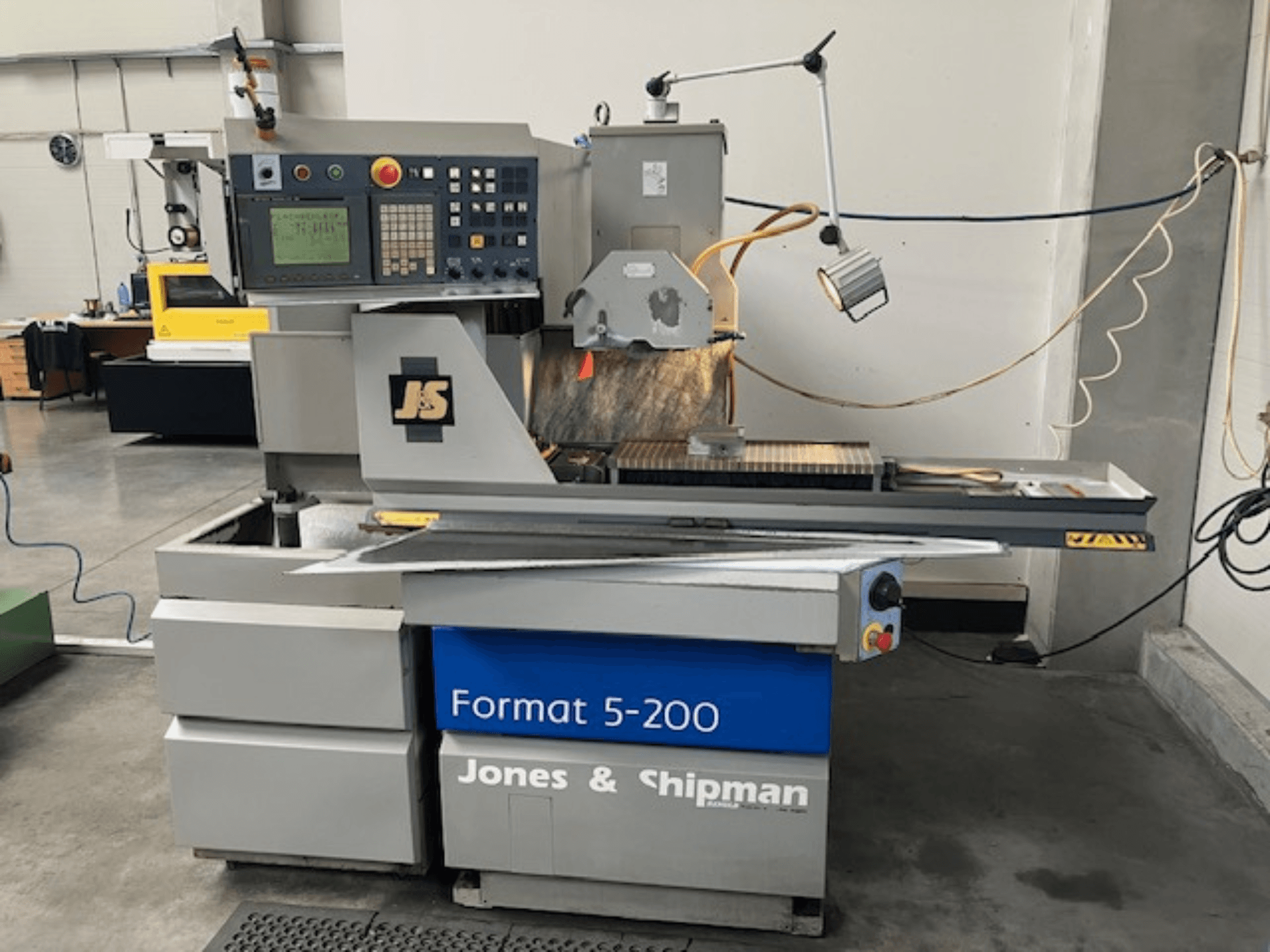 Vlak slijpmachine Jones & Shipman Format 5-200 in zijaanzicht, met bedieningspaneel, slijpschijf en werktafel.