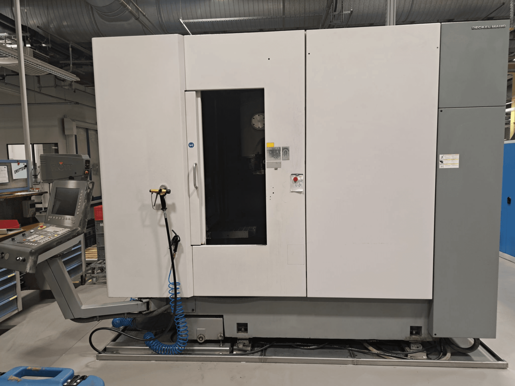 DECKEL MAHO DMP 60V verticaal bewerkingscentrum, vooraanzicht met bedieningspaneel en hoofdbehuizing, waarbij de deur openstaat voor toegankelijkheid.