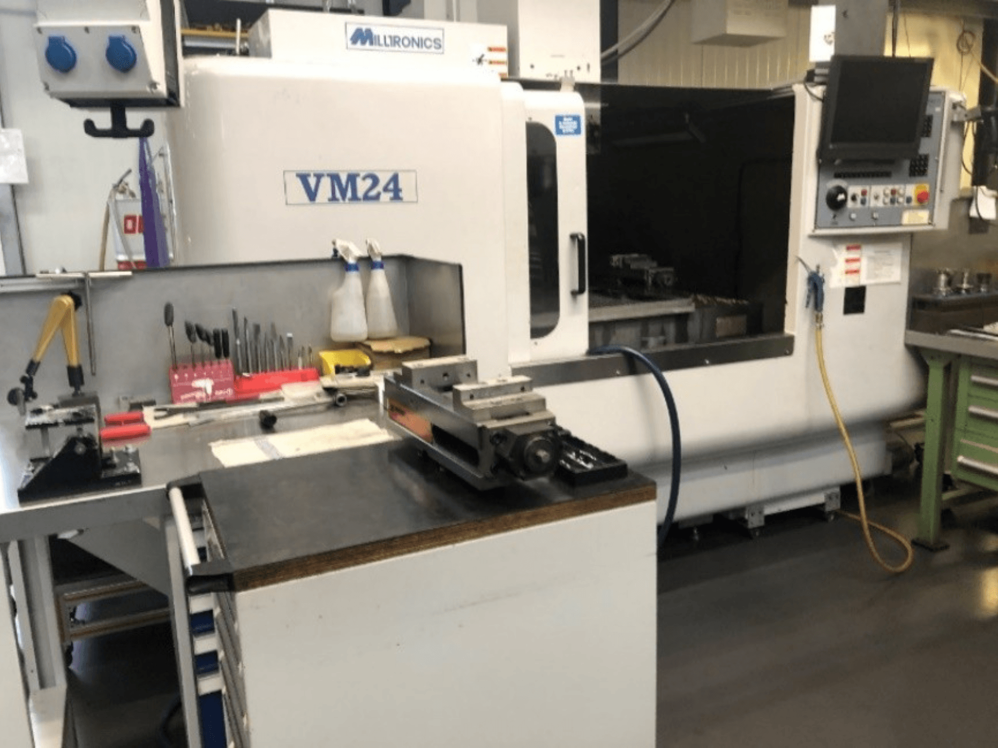 Werkruimte met de Milltronics VM24 CNC machine. Vooraanzicht met gereedschap en apparatuur op een werkbank.