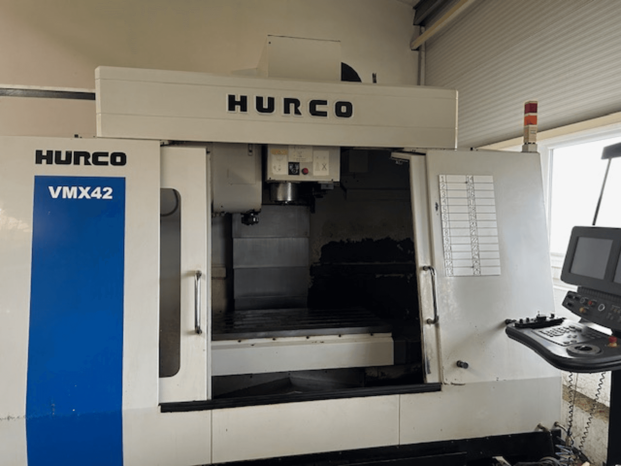 Hurco VMX42 CNC machine in vooraanzicht, met bedieningspaneel, spindel en werkgebied; toont operationele lay-out.