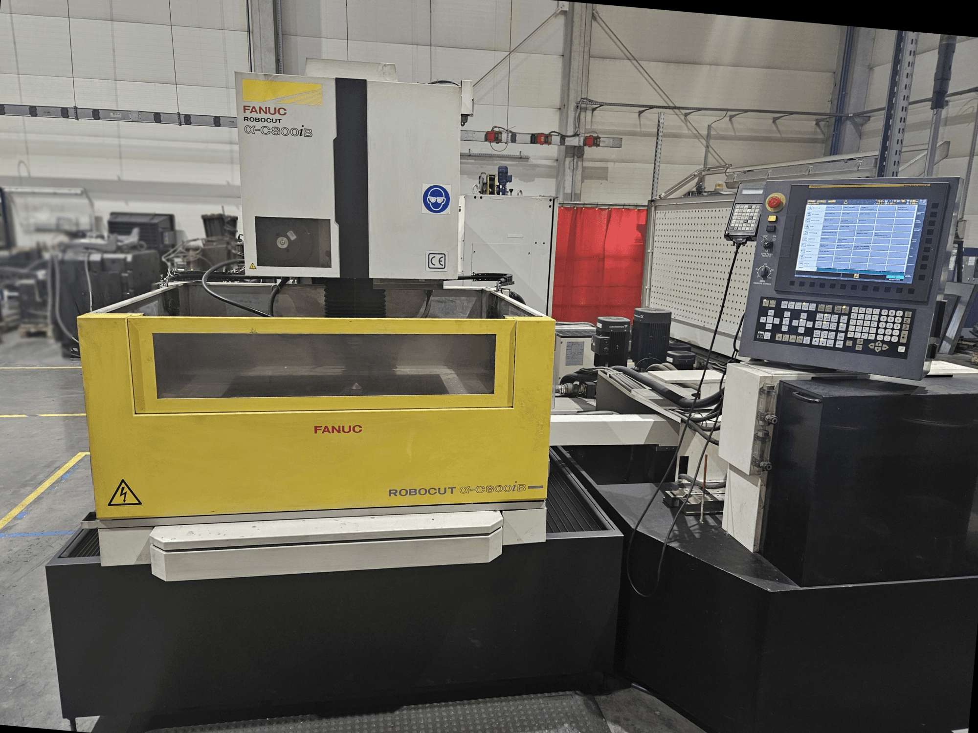 Vooraanzicht van FANUC Robocut α-C600iB met een geel en grijs machinelichaam, CNC bedieningspaneel en operationeel display.