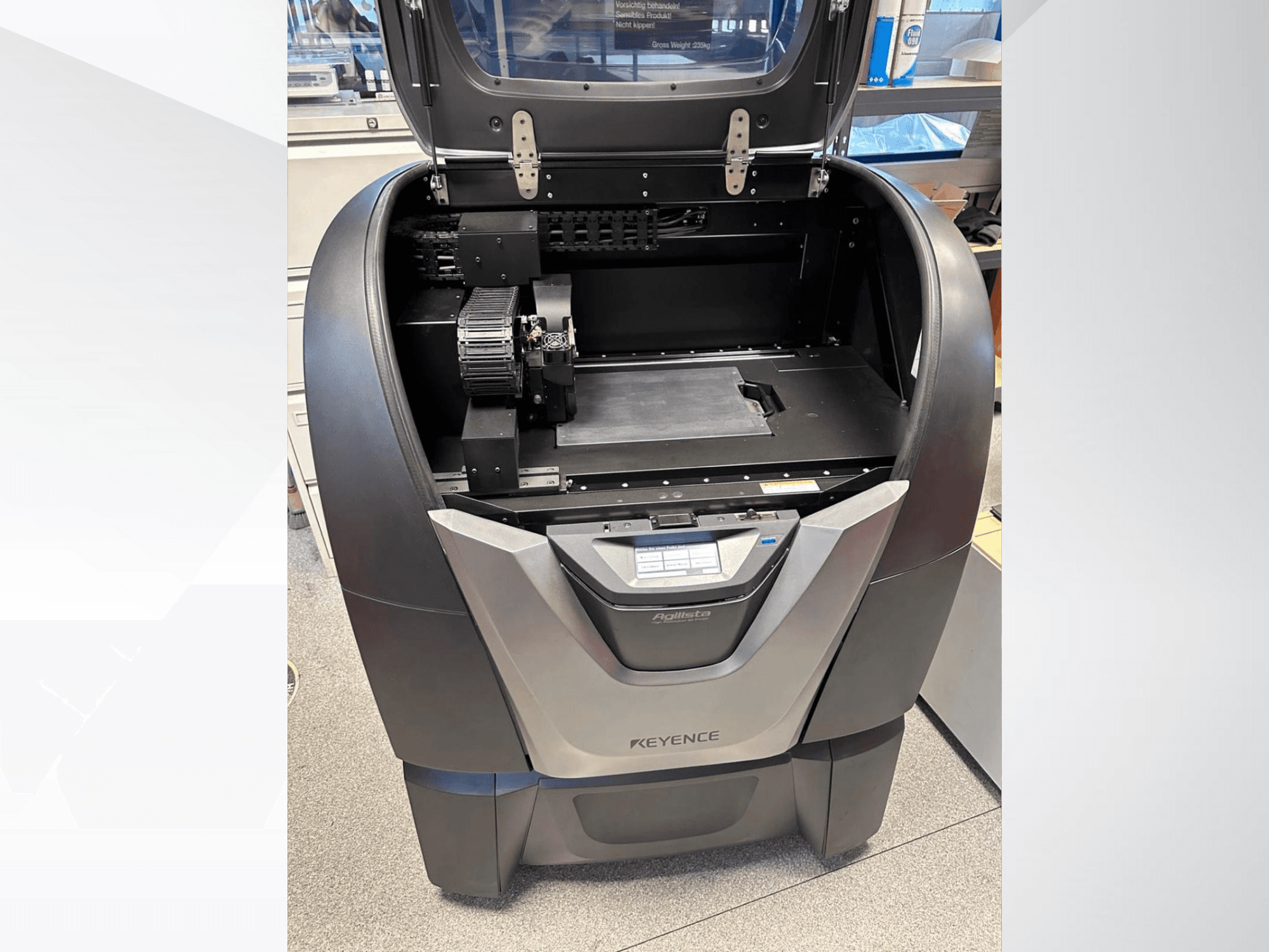 KEYENCE Agilista 3D printer, vooraanzicht, toont open bovenkant, groot bouwplatform en interne mechanische componenten.