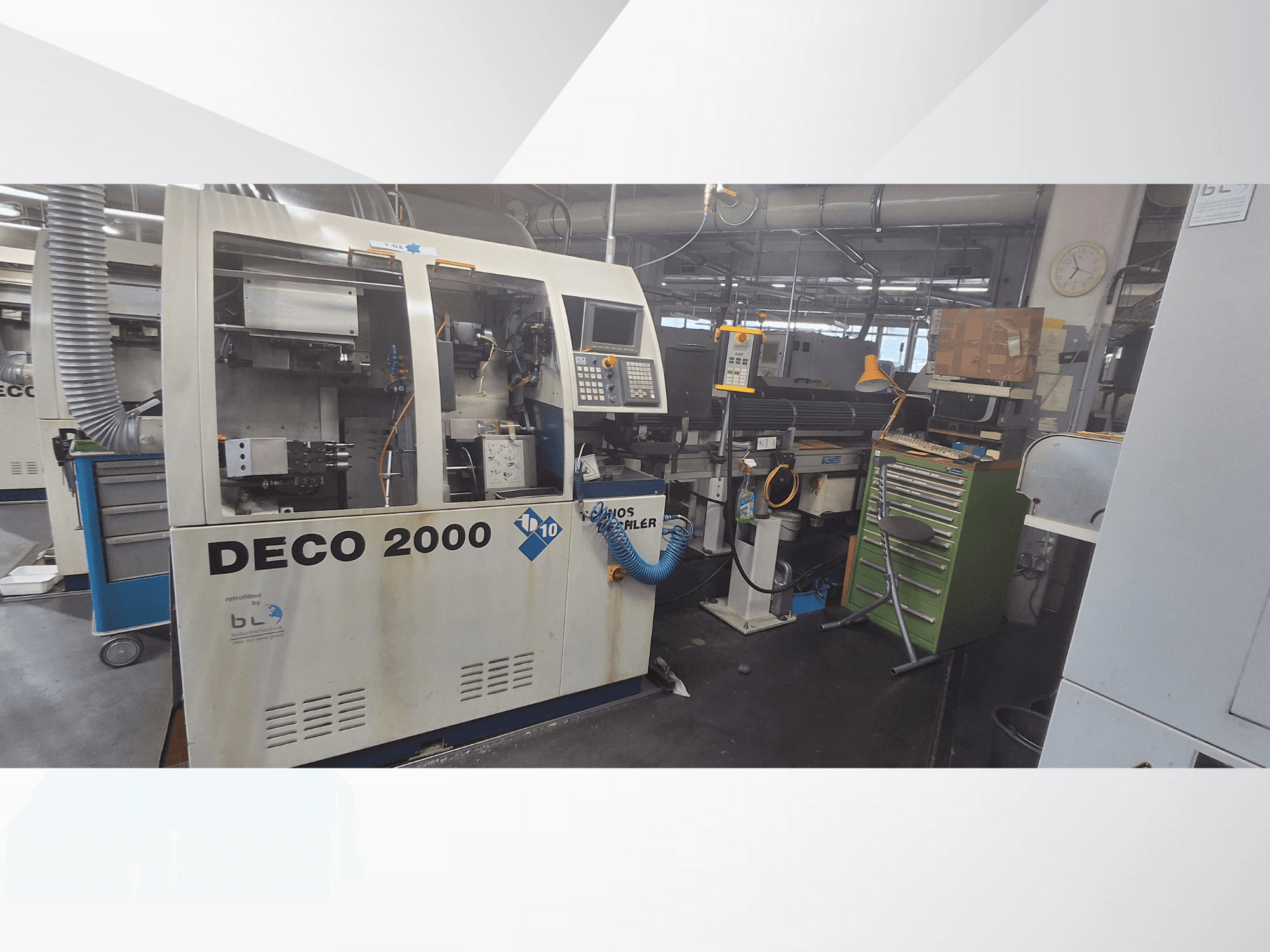 DECO 2000 machine gezien vanaf de voorkant, met bedieningspaneel, leidingen en een rommelige werkruimte met gereedschap en dozen.