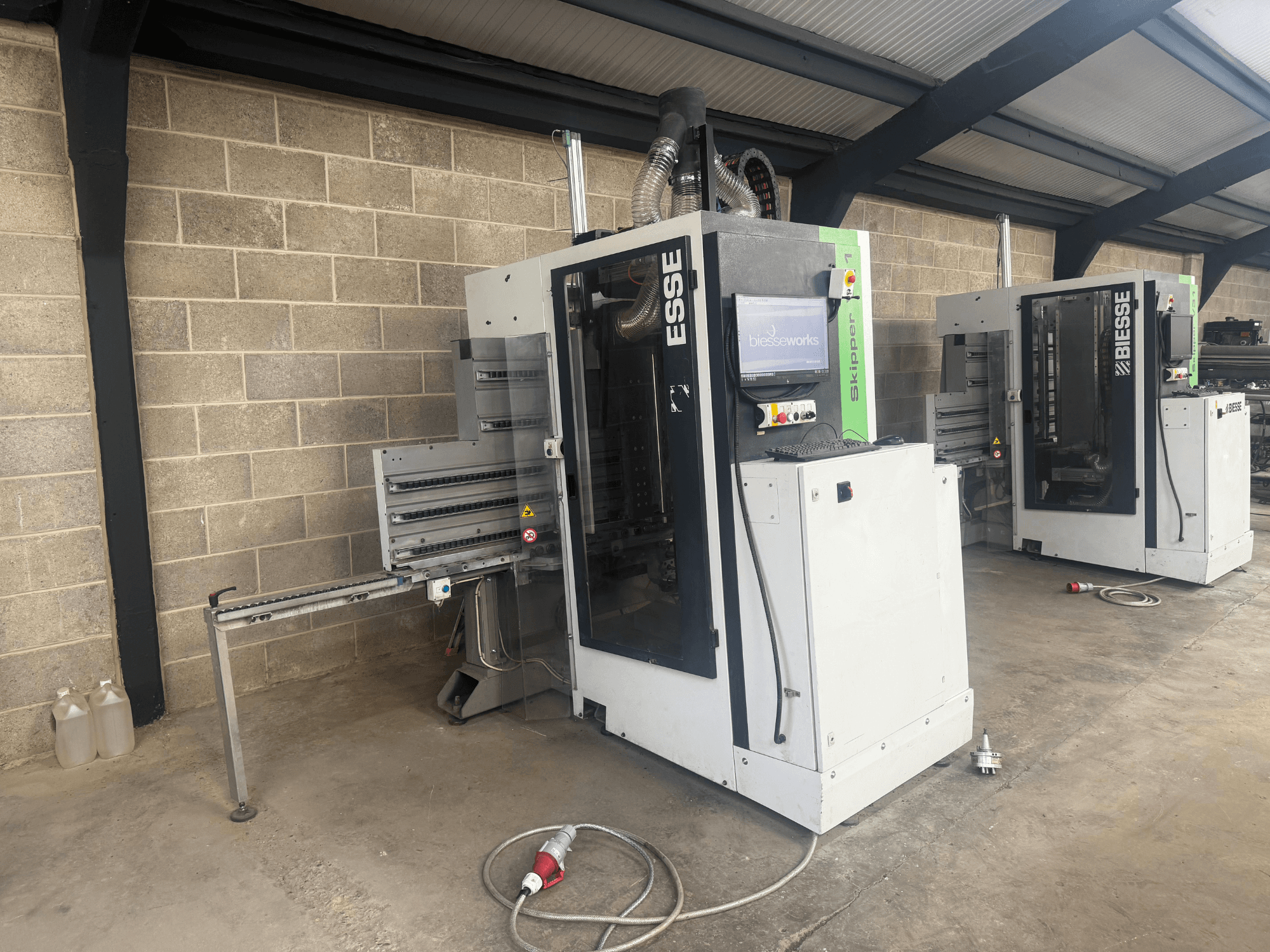 BIESSE Skipper v31 houtboormachine in zijaanzicht, met bedieningspaneel en aangrenzende machines, opgesteld in een werkplaats.