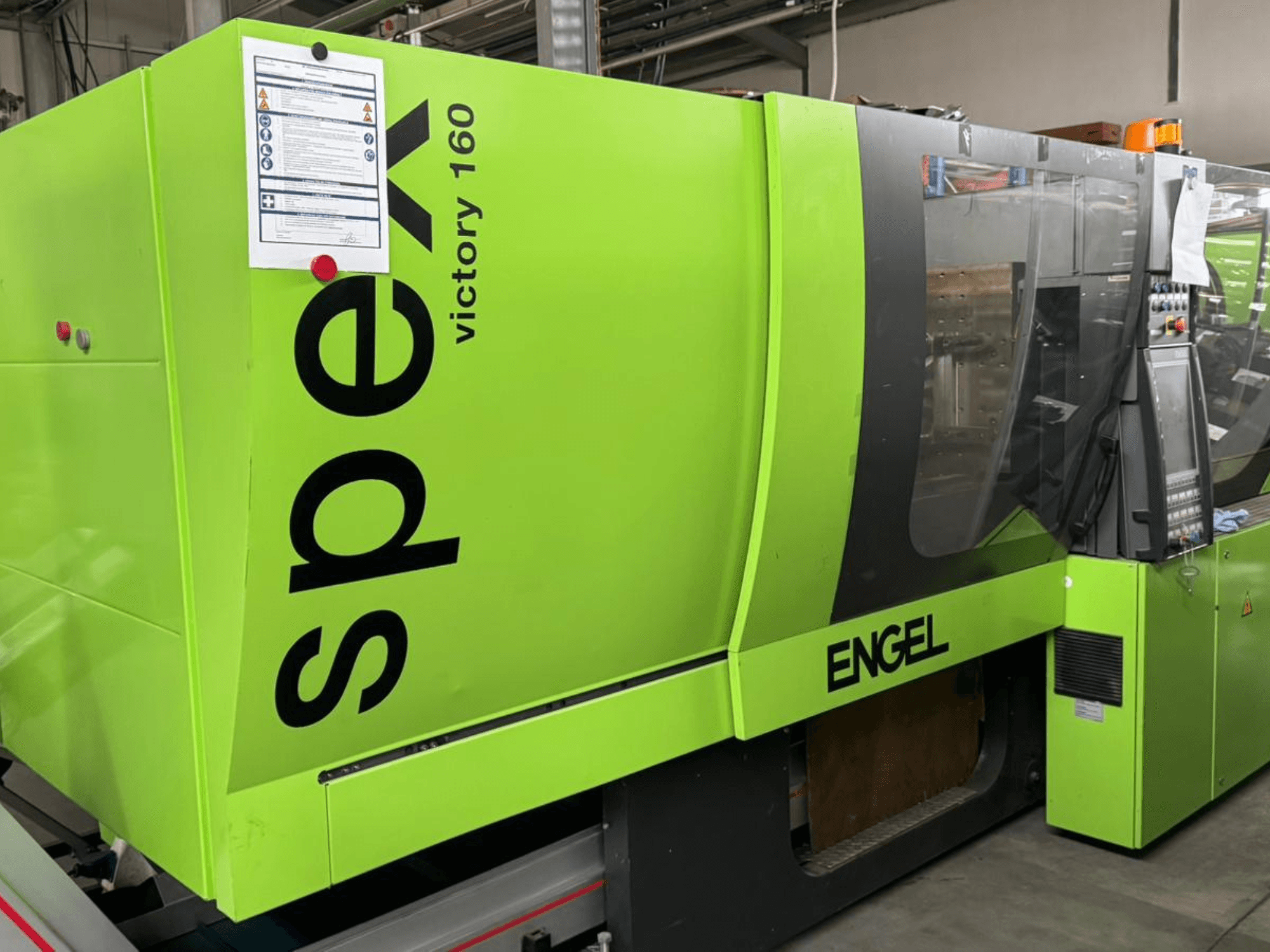 Heldergroene ENGEL Victory 160 spuitgietmachine, zijaanzicht, bedieningspaneel en veiligheidsborden zichtbaar.