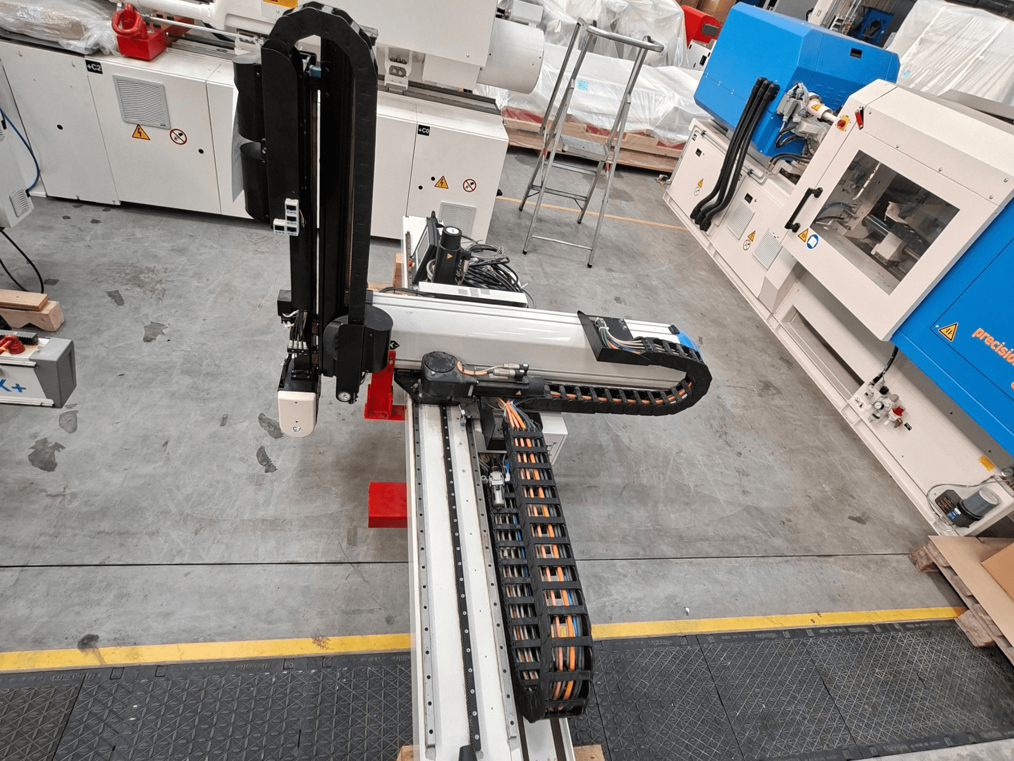Kunststofverwerkingsmachine Krauss Maffei LRX150-MC5 in bovenaanzicht, met de robotarm en de kabelgoot op de fabrieksvloer.