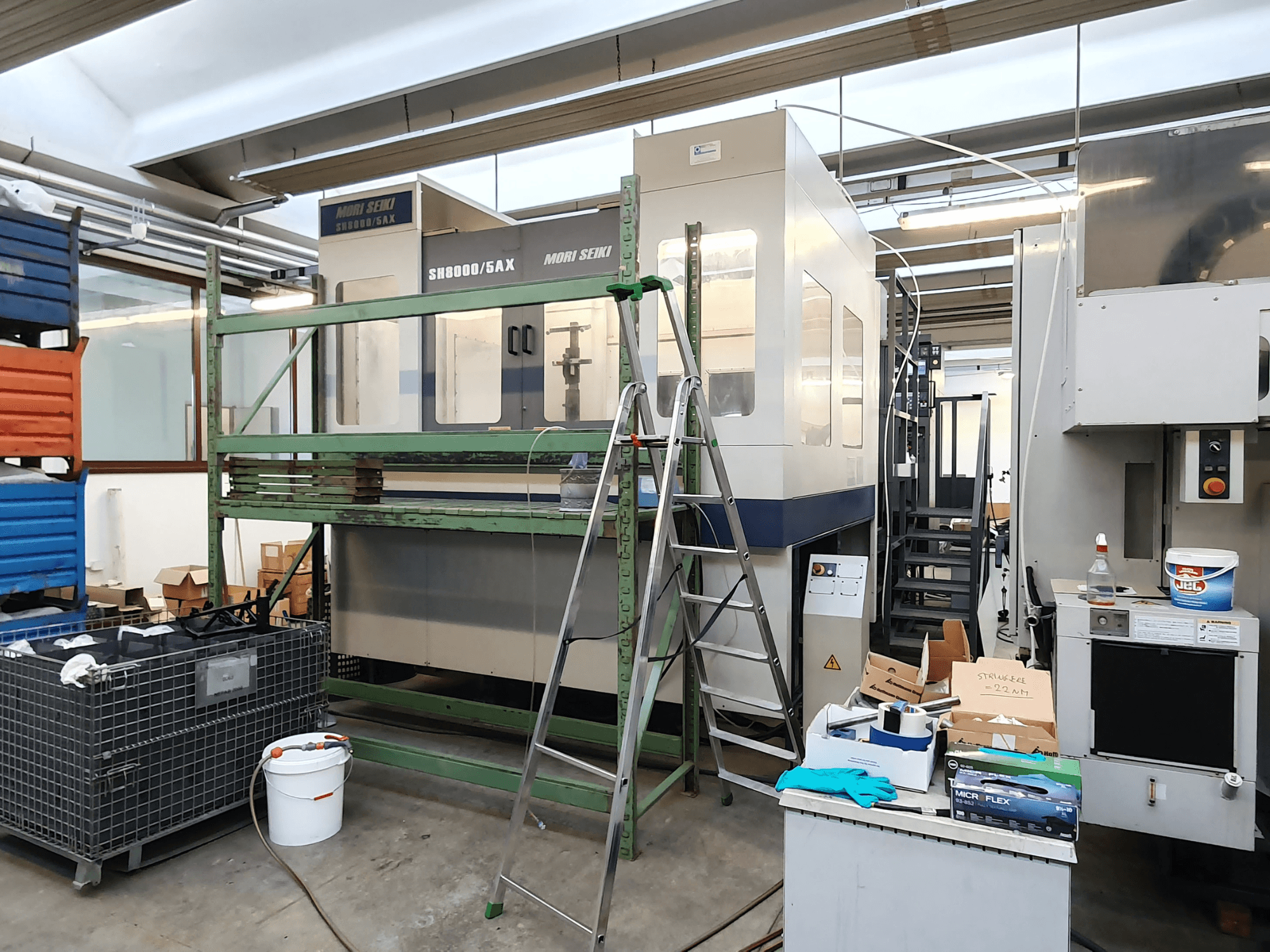 Mori Seiki SH-8000/5AX CNC machine in een werkplaats, vooraanzicht, met werkplaatsgereedschap en opbergdozen in de buurt.