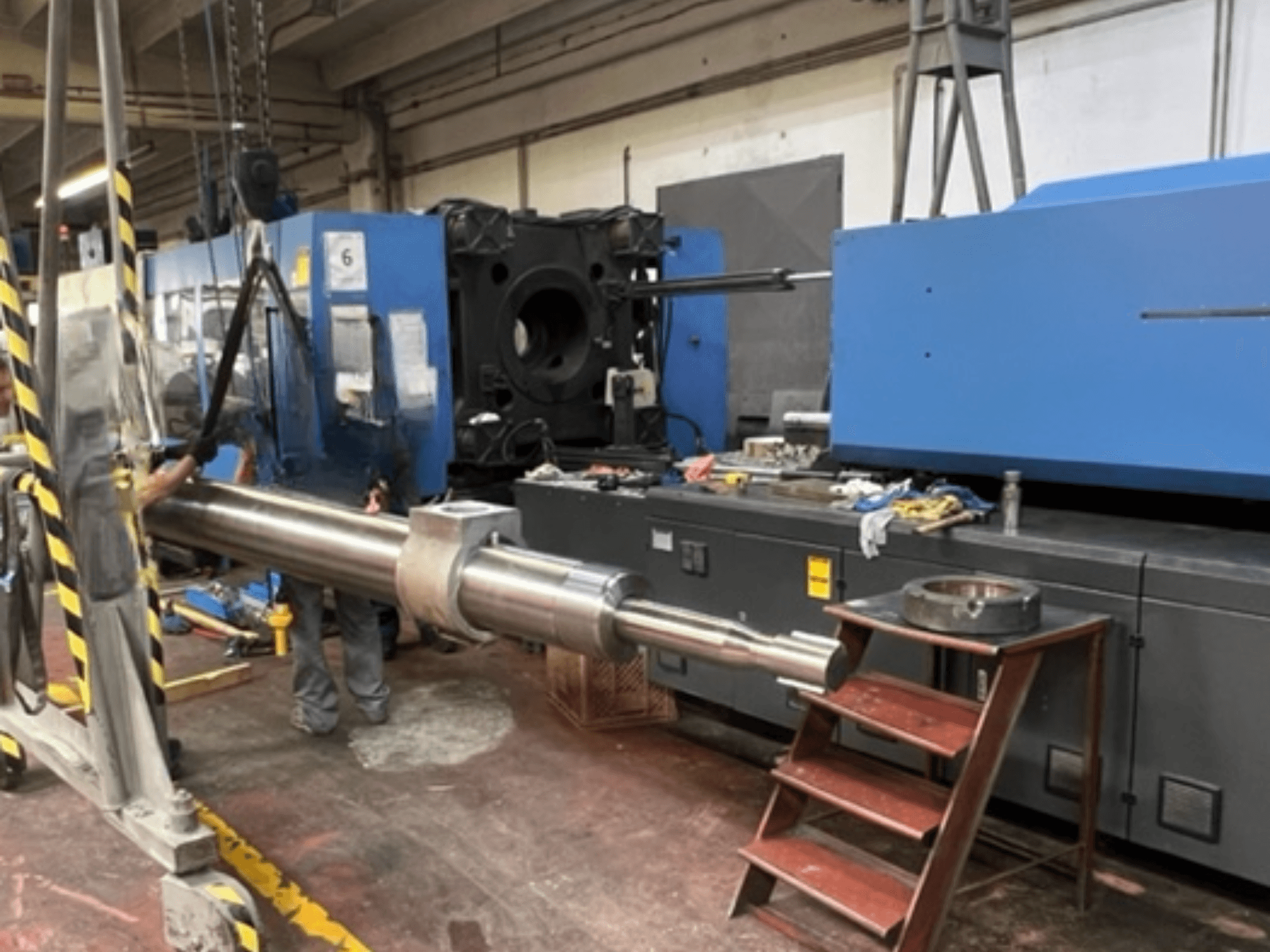 Hydraulische spuitgietmachine HAITIAN SA8000, afgebeeld in zijaanzicht terwijl een grote hydraulische stang wordt opgetild.