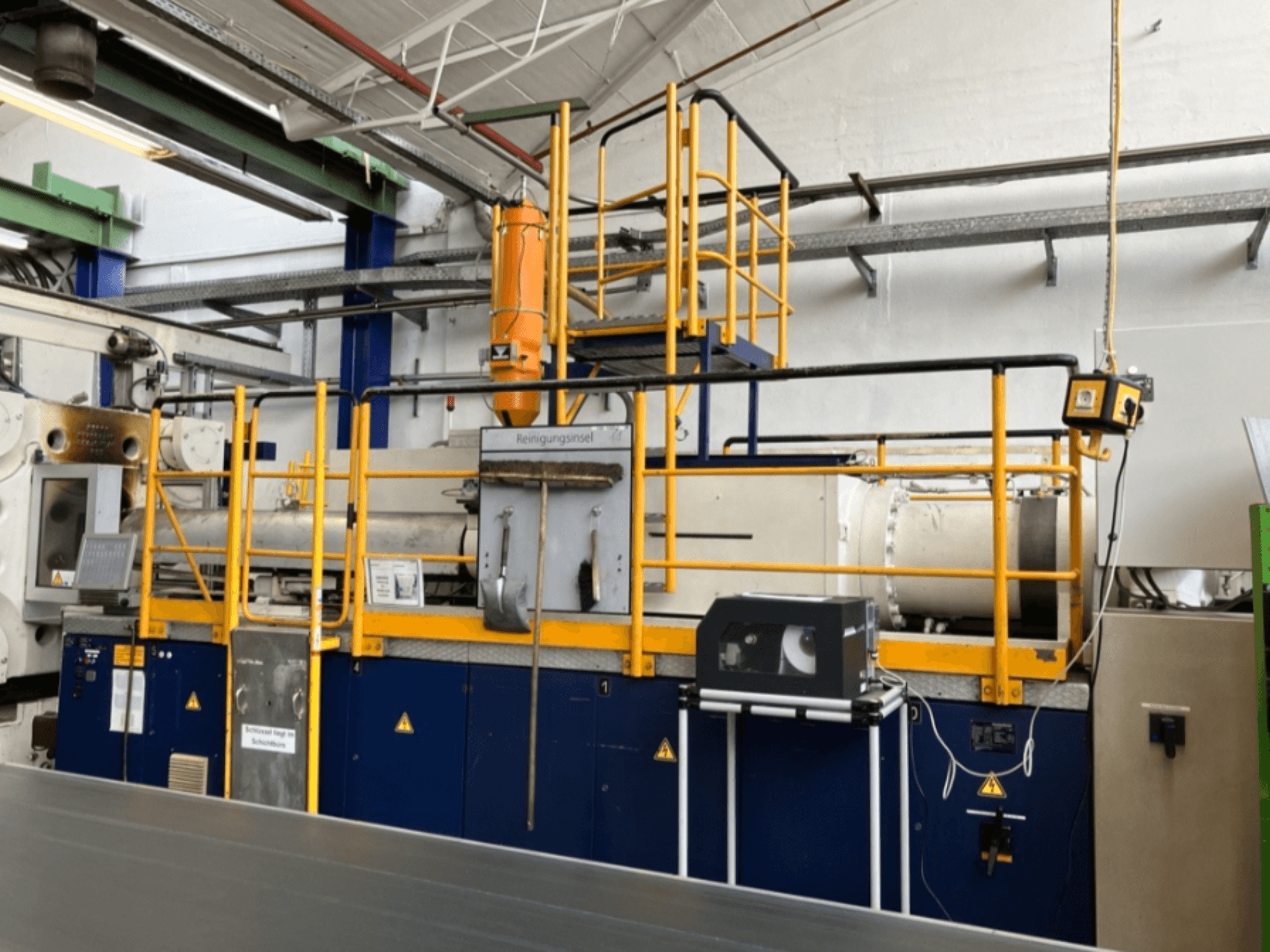 Krauss Maffei 1000-8000 M hydraulische spuitgietmachine, zijaanzicht met veiligheidsreling en bedieningspaneel zichtbaar.