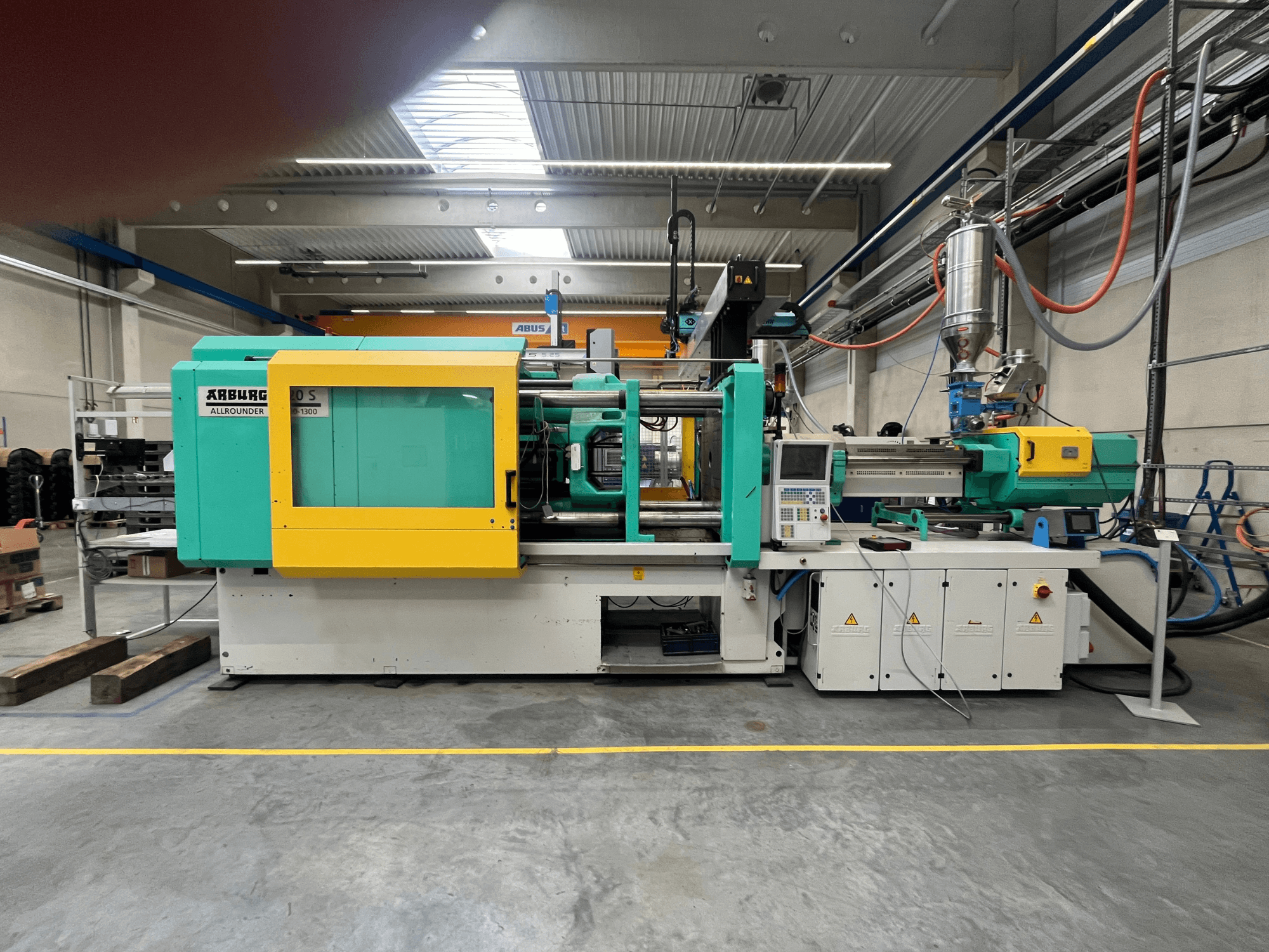 ARBURG Allrounder 370S kunststof spuitgietmachine, zijaanzicht, met groene en gele behuizing, bedieningsinterface zichtbaar.