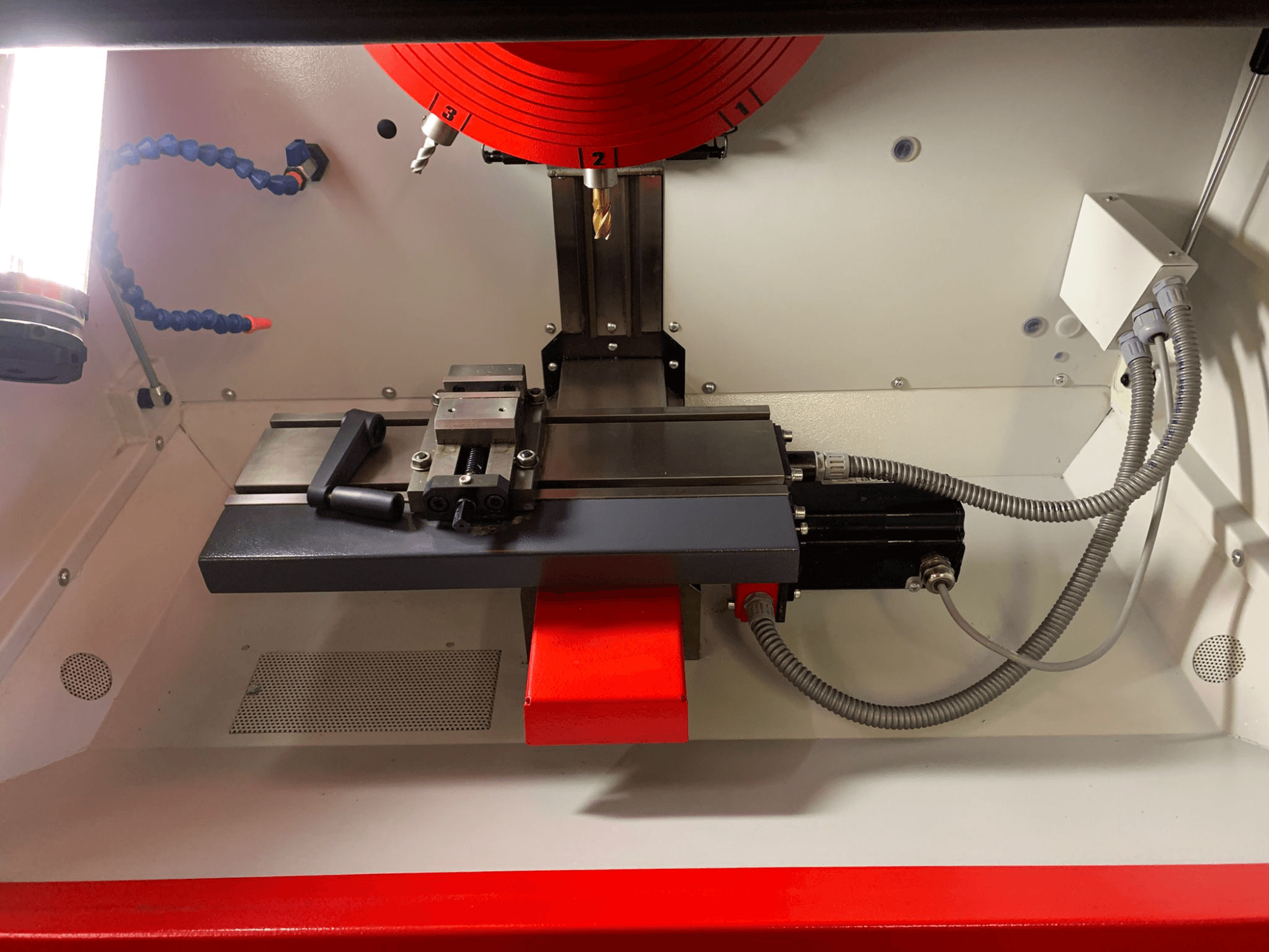 Binnenkant van een bewerkingsgereedschap, met een lineaire geleider, spindel en bedrading. Vooraanzicht toont componenten en rode accenten.