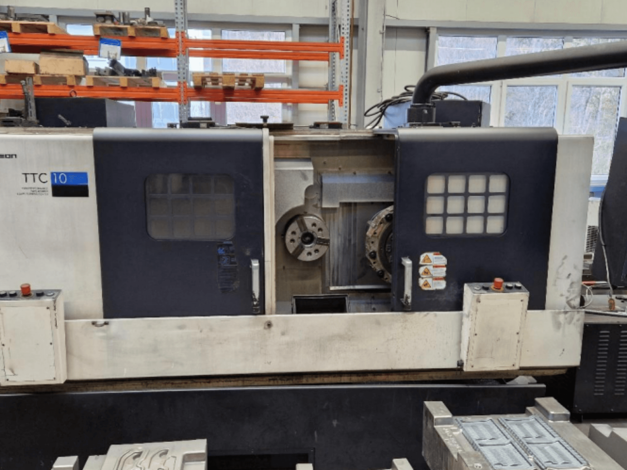 Vooraanzicht draaibank TTC 10, met bedieningspaneel, zichtbare klauwplaten en werkruimte met metalen onderdelen.