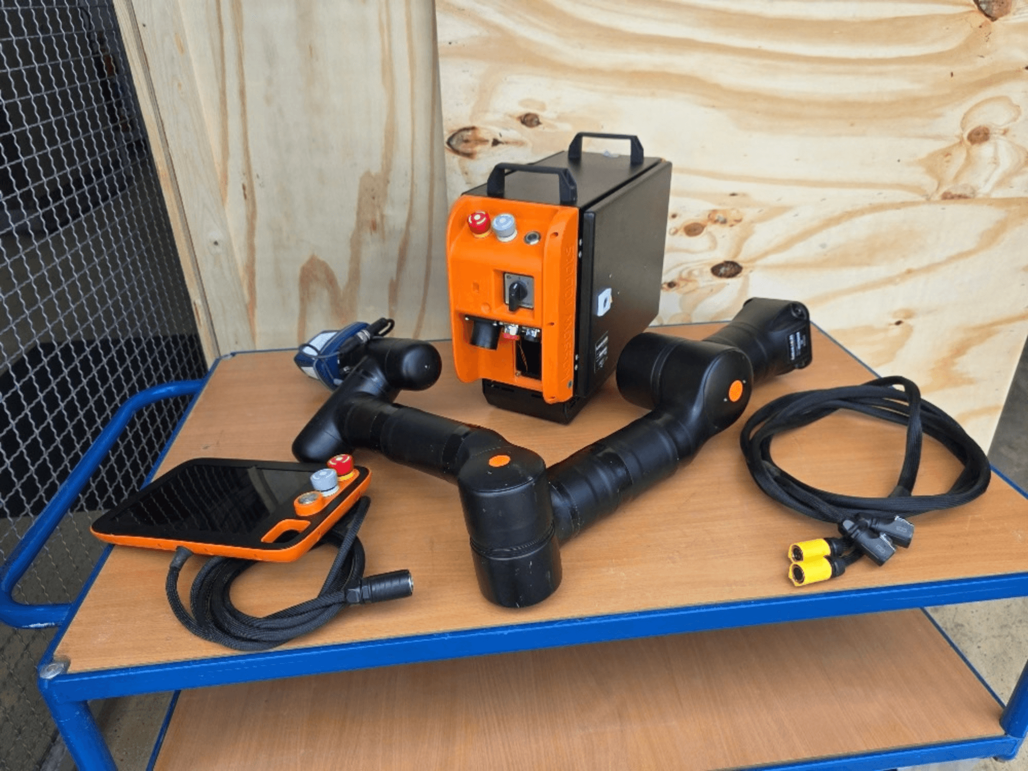 KASSOW ROBOTS KR810 collaboratieve robot, vooraanzicht, inclusief besturingseenheid, kabels en aansluitingen op een houten tafel.