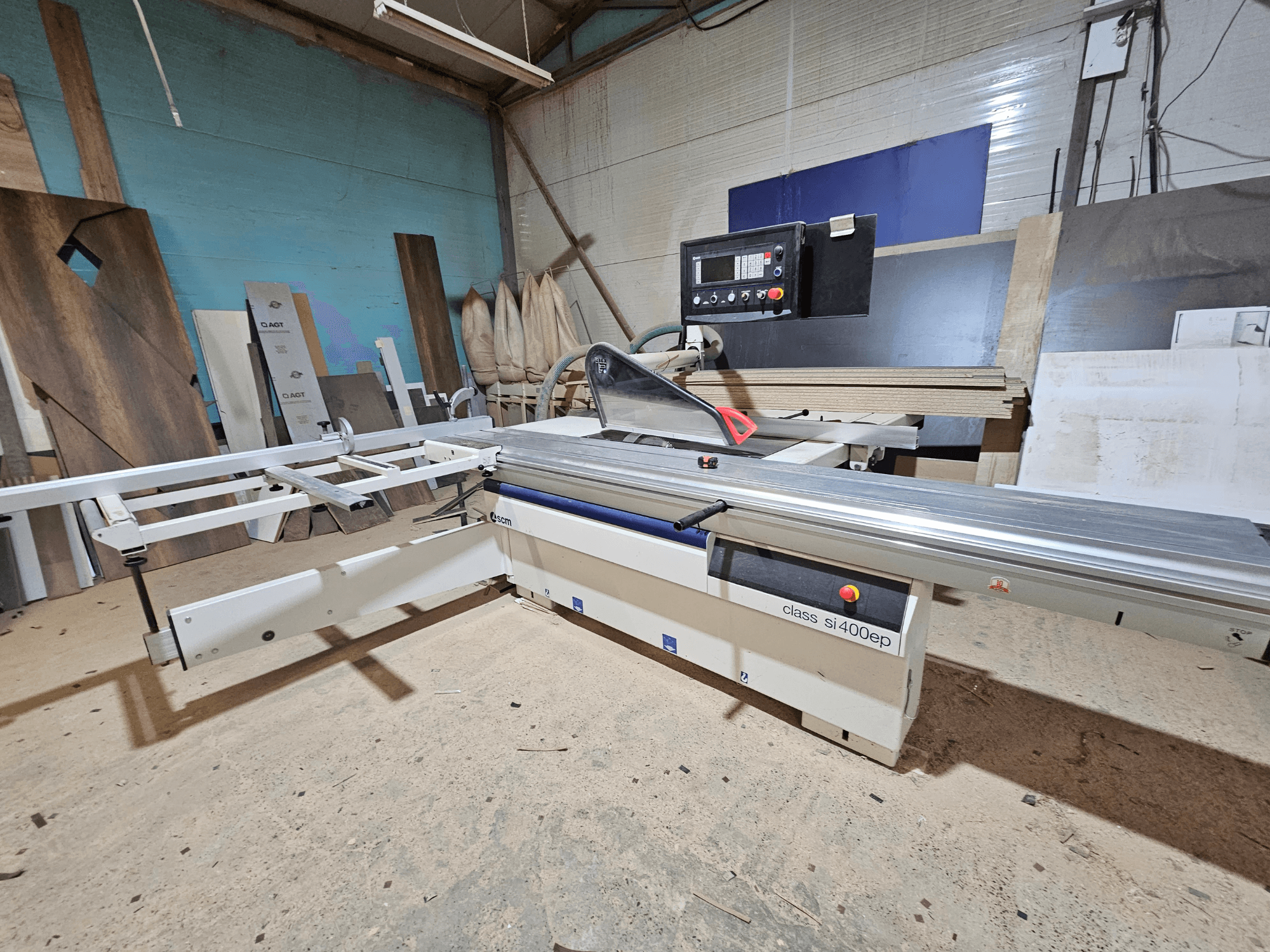 Plaatzaag van het type SI400EP, vooraanzicht, met verstelbare geleider, op een zanderige werkvloer, omringd door houten panelen.