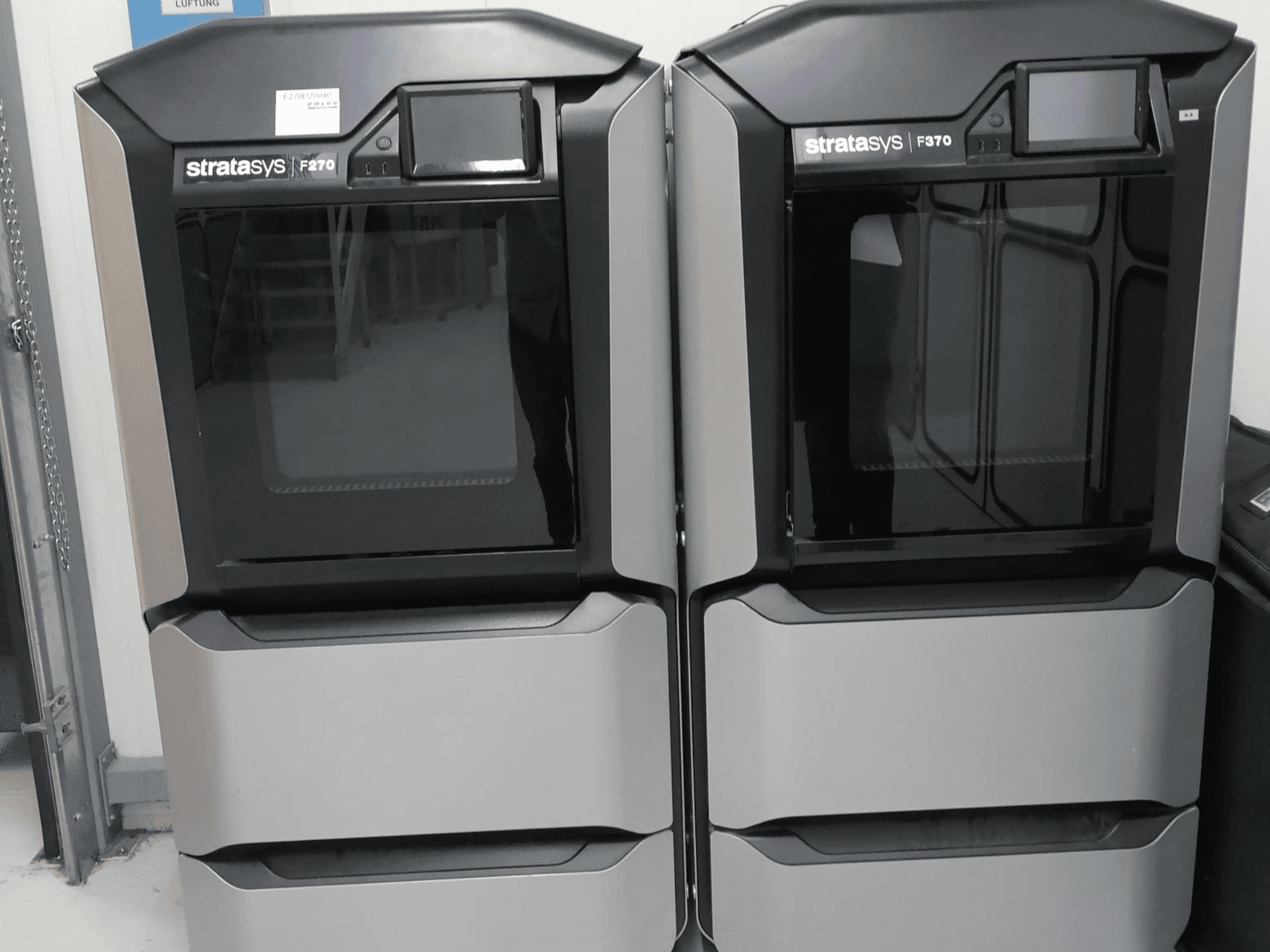 Stratasys F370 dual plastic 3D printers in vooraanzicht, met een gestroomlijnd zwart en zilver design en bedieningsschermen.