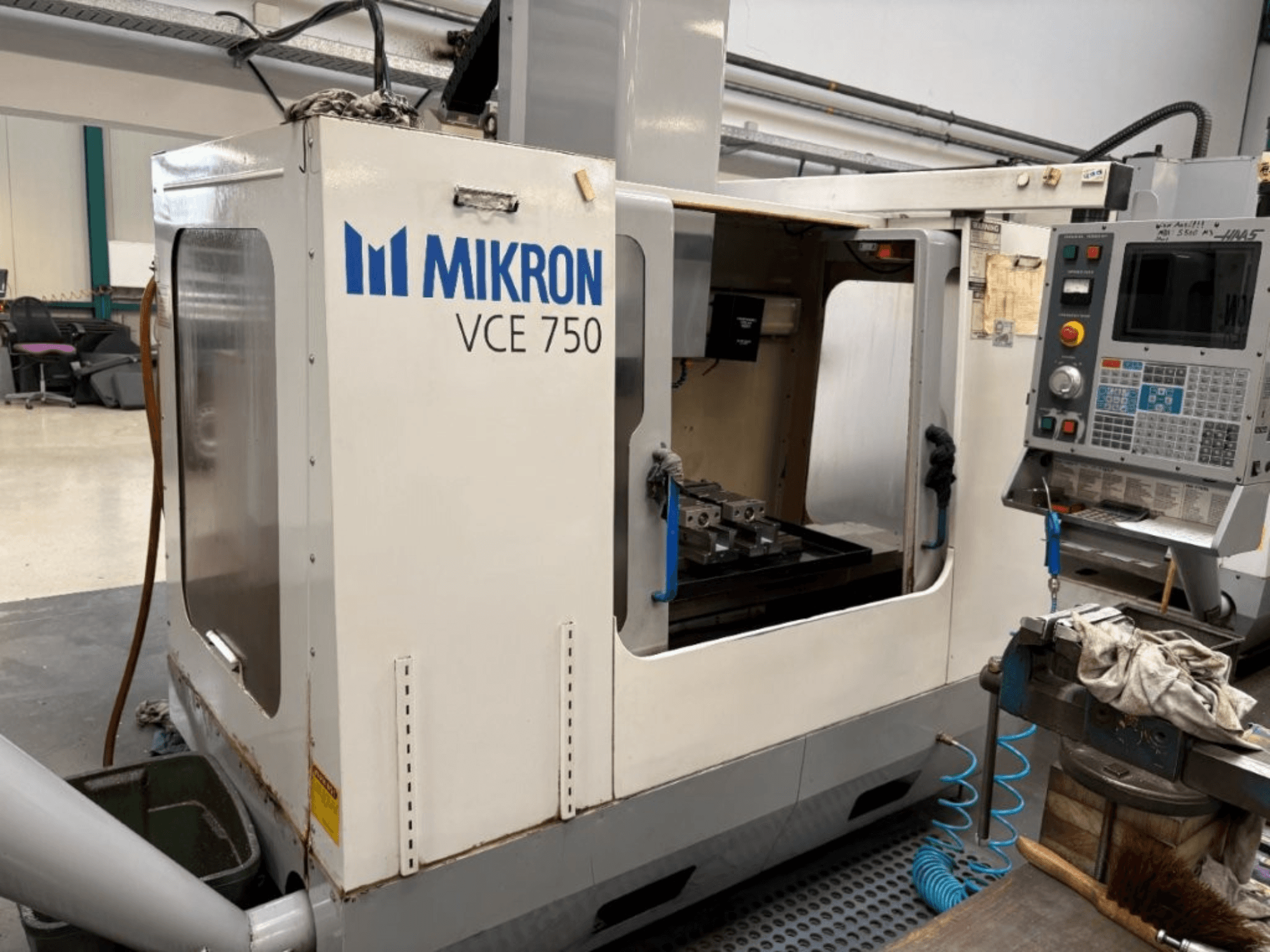 Mikron VCE 750 CNC freesmachine vooraanzicht, met een bewerkte werktafel en bedieningspaneel met diverse knoppen en schermen.
