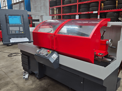 Rode CNC draaibank met bedieningspaneel, vooraanzicht; voorzien van transparant deksel, gereedschaphouder en opbergladen.