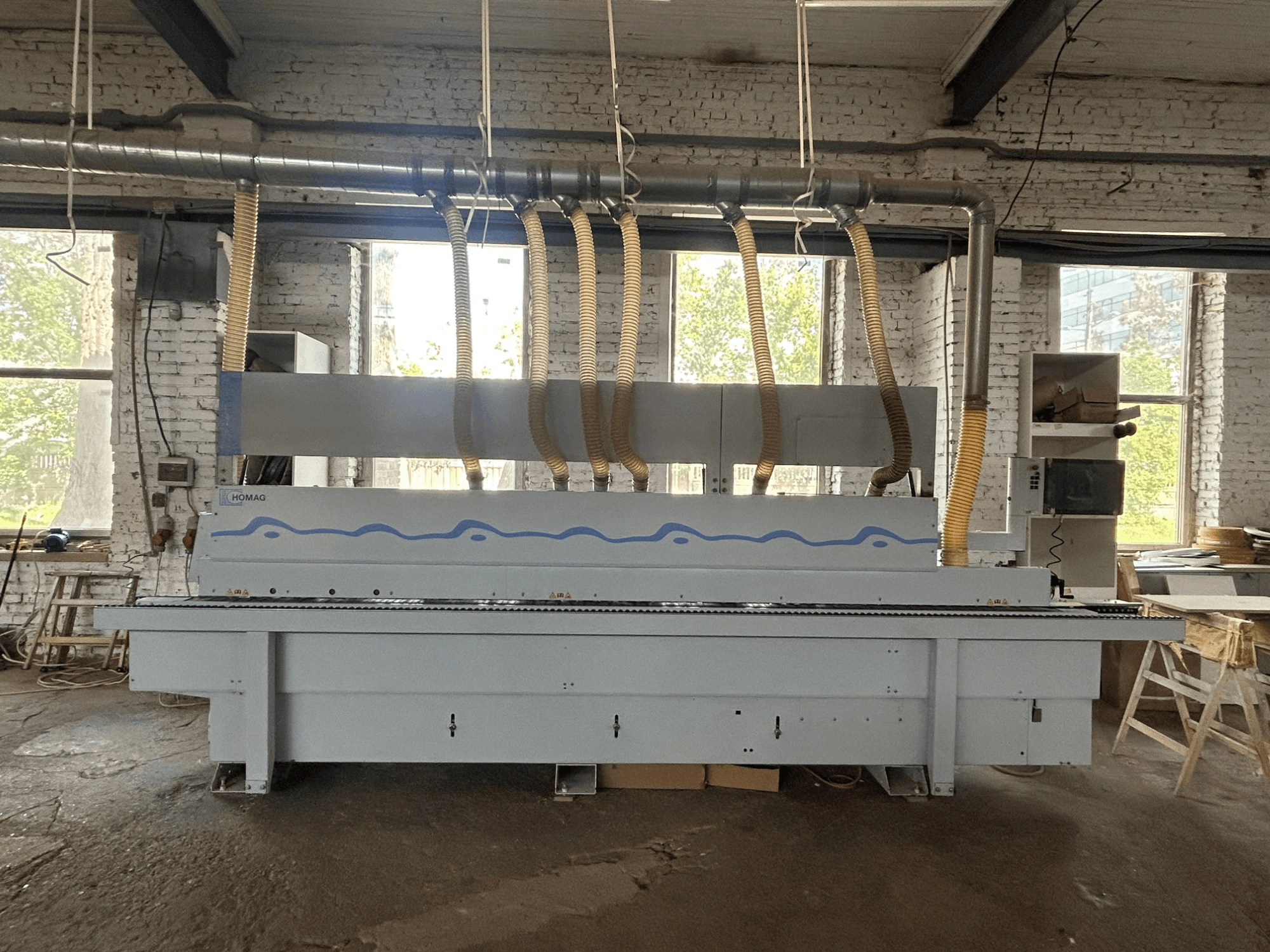 Vooraanzicht van de HOMAG Optimat KDF 440 C kantenlijmmachine, met een grote machine voorzien van stofafzuigslangen en een bedieningspaneel.