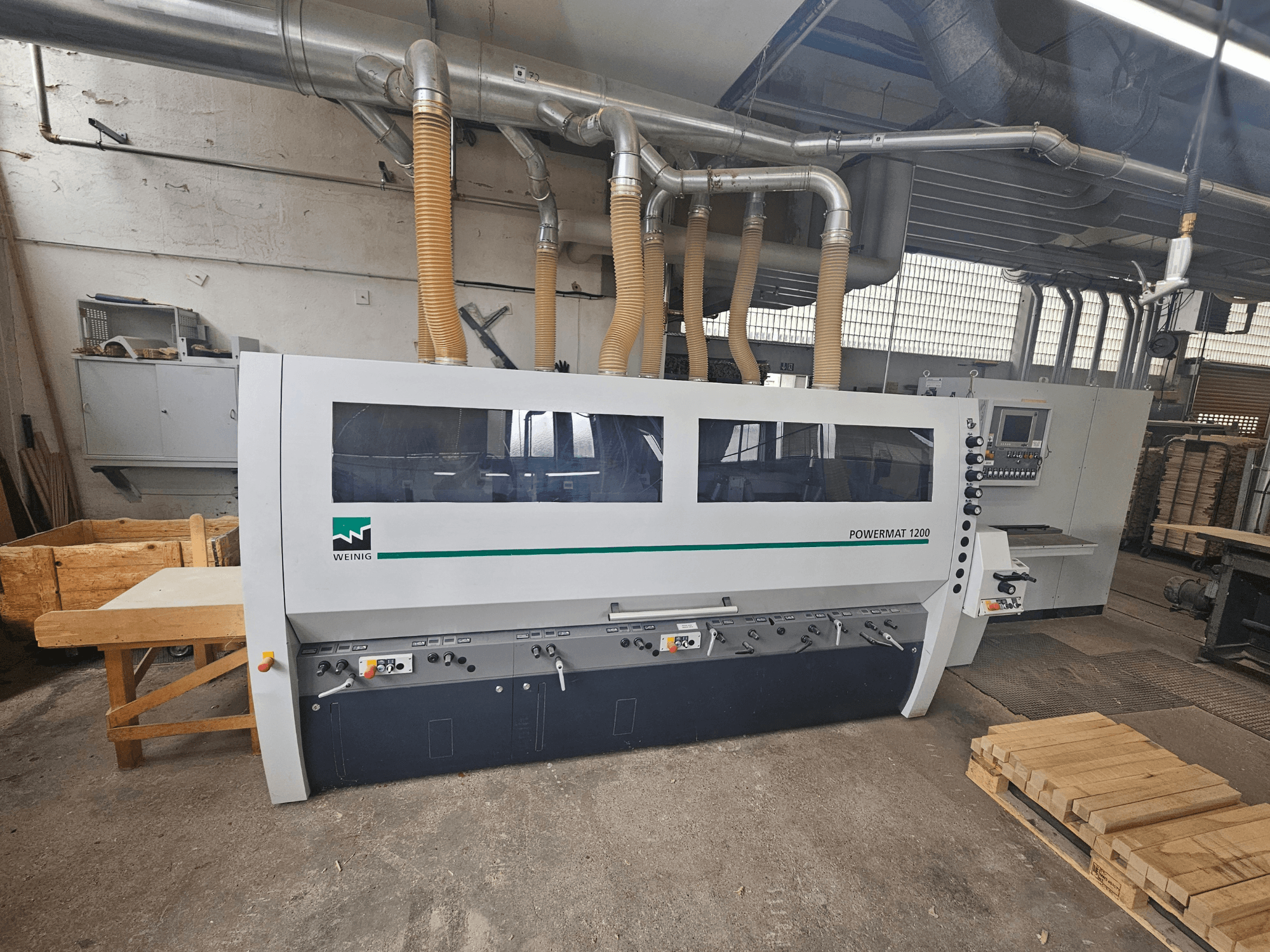 Weinig Powermat 1200 houtbewerkingsmachine, vooraanzicht, met bedieningspaneel en houtstapels in een werkplaats.