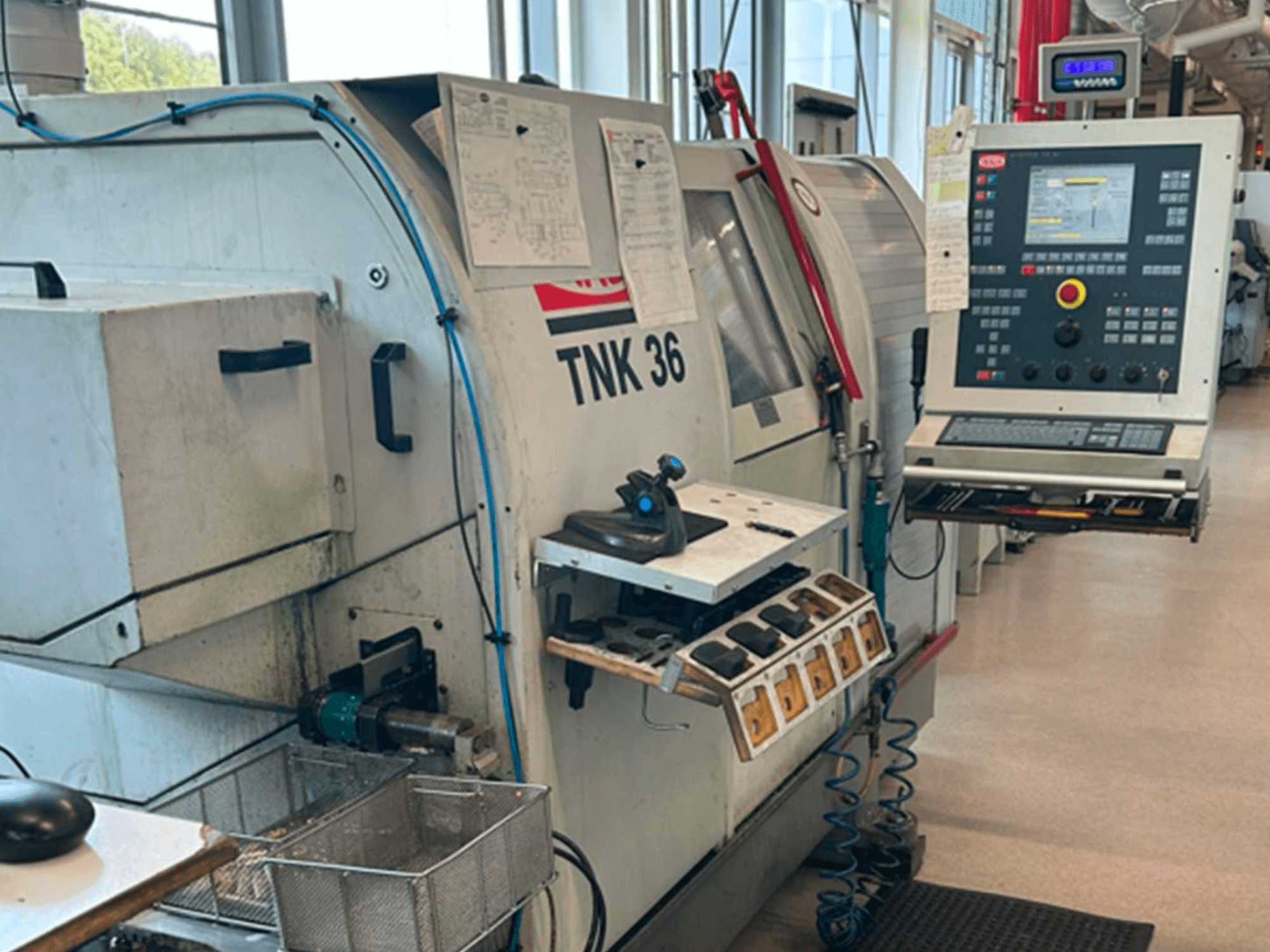 Horizontaal aanzicht van de TRAUB TNK 36-draaimachine, met bedieningspaneel, gereedschapshouder en werkgebied.