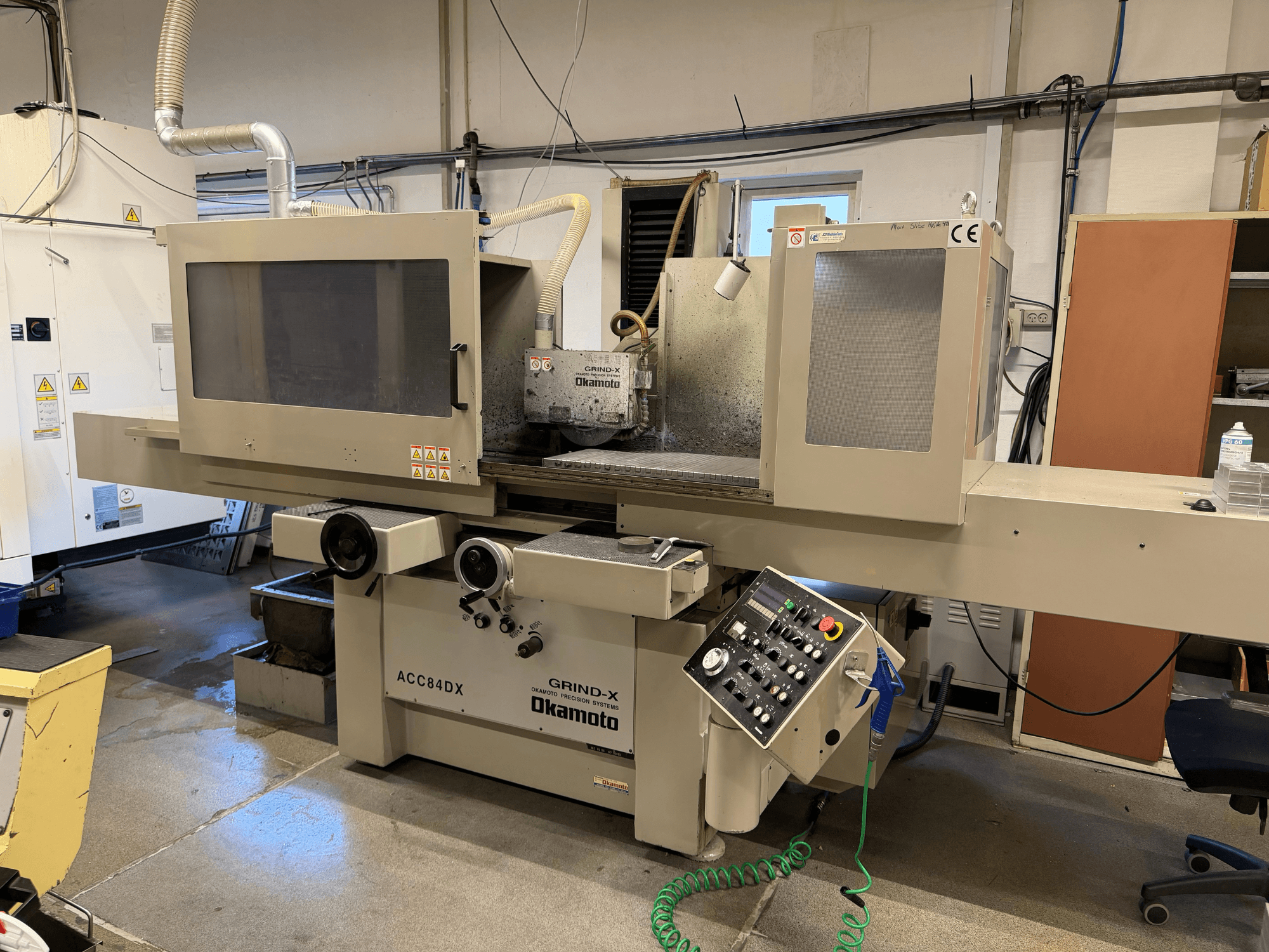 Vooraanzicht van de OKAMOTO ACC 84DX vlakslijpmachine, met bedieningspaneel en koelsysteem.