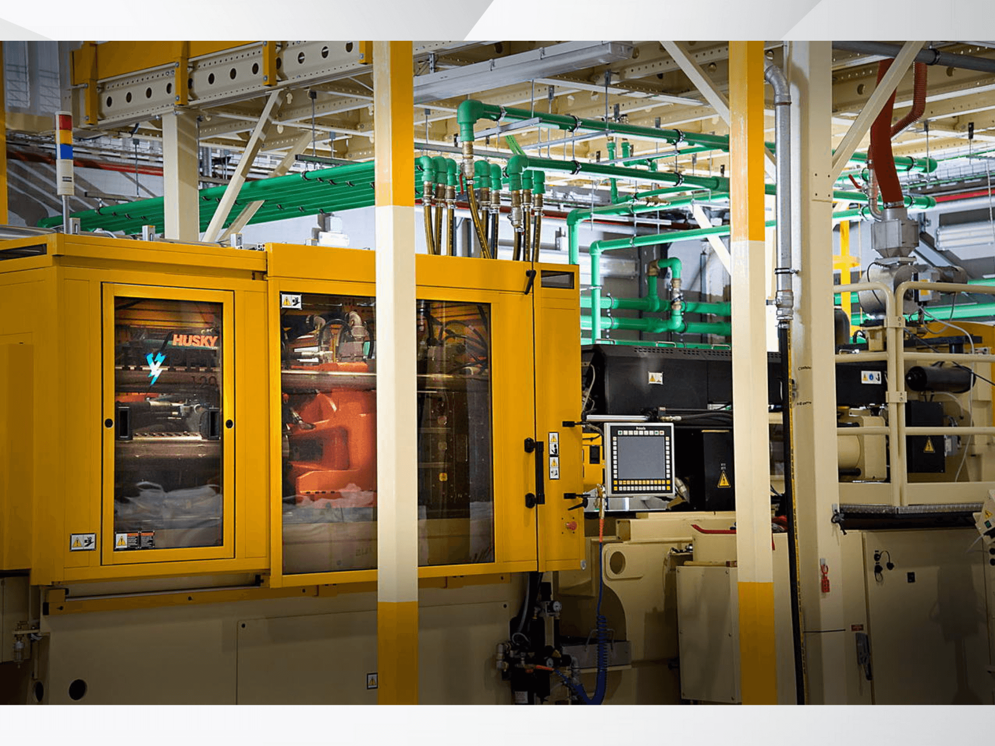 Husky industriële machine in geel, vooraanzicht met bedieningspaneel en interne mechanismen tegen een fabrieksachtergrond.