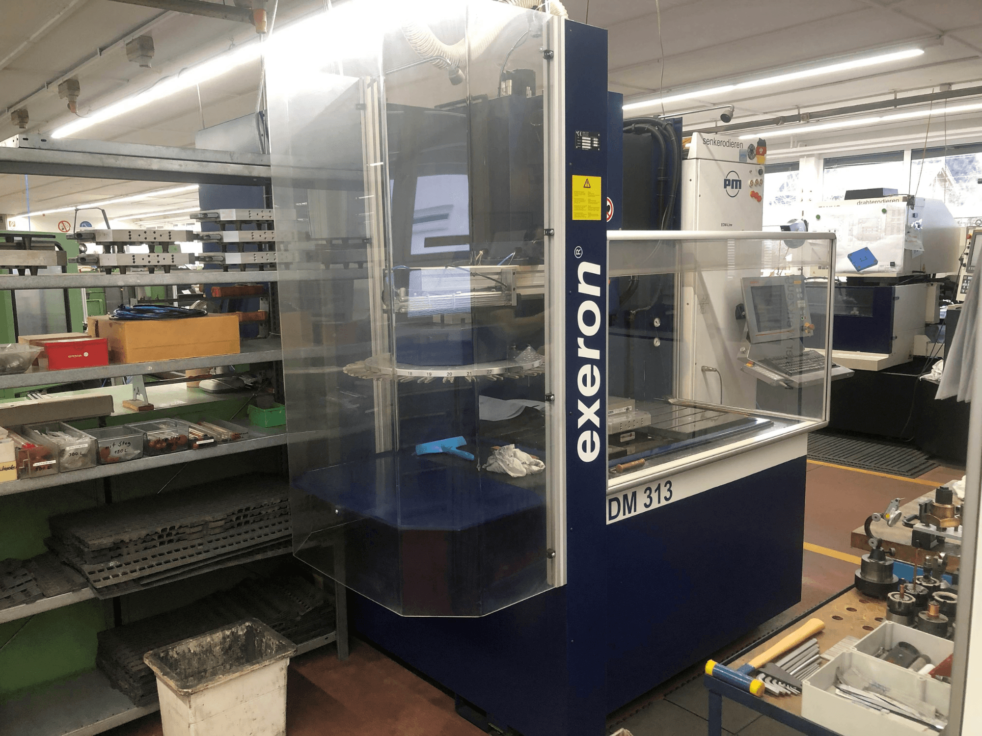 Exeron EDM 313 stansmachine in een werkplaats, vooraanzicht met duidelijke behuizing en bedieningspaneel.