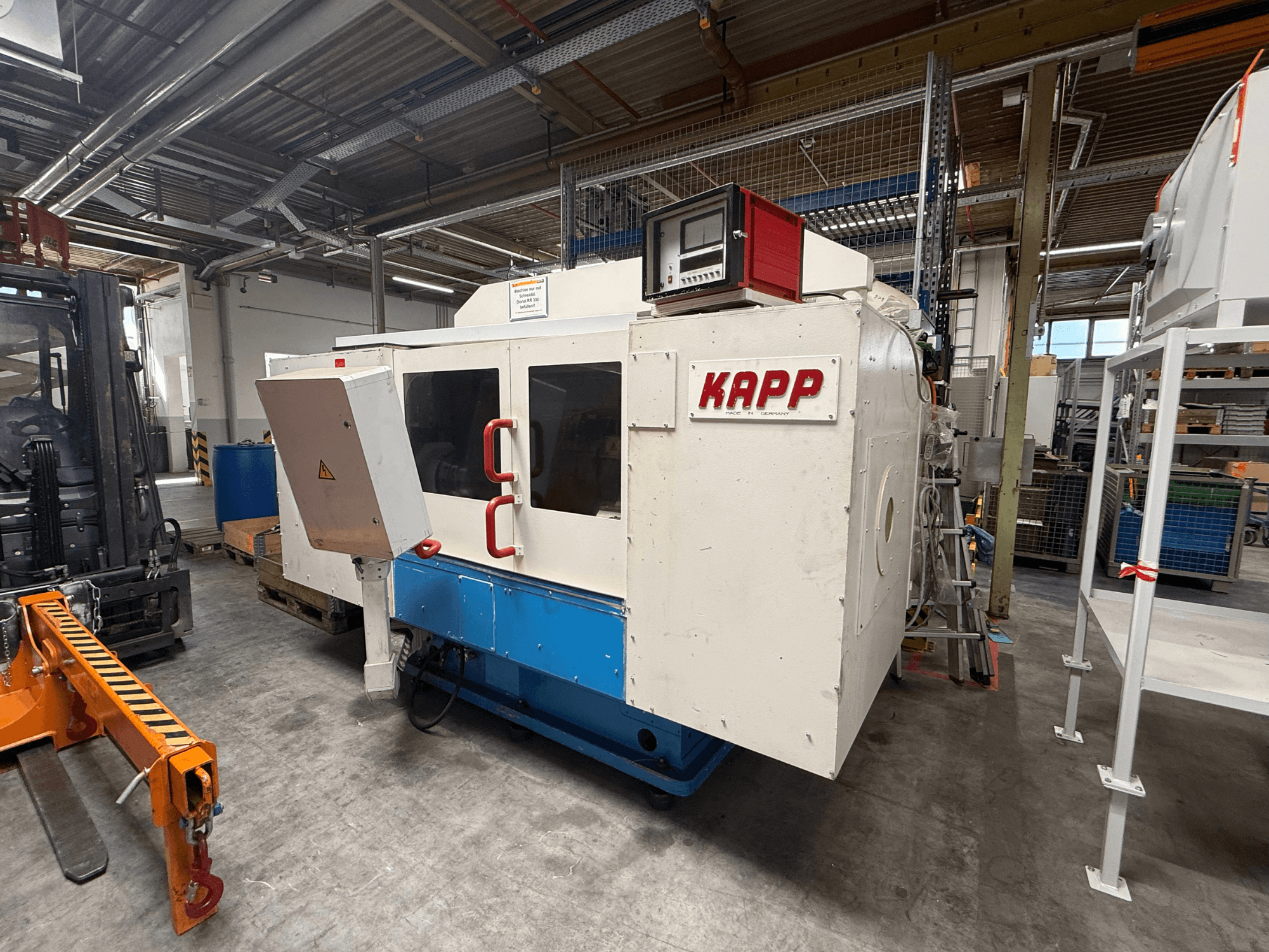 De cilindrische slijpmachine KAPP RNS 55, afgebeeld in zijaanzicht, met bedieningspaneel en veiligheidsafscherming in een werkplaatsomgeving.