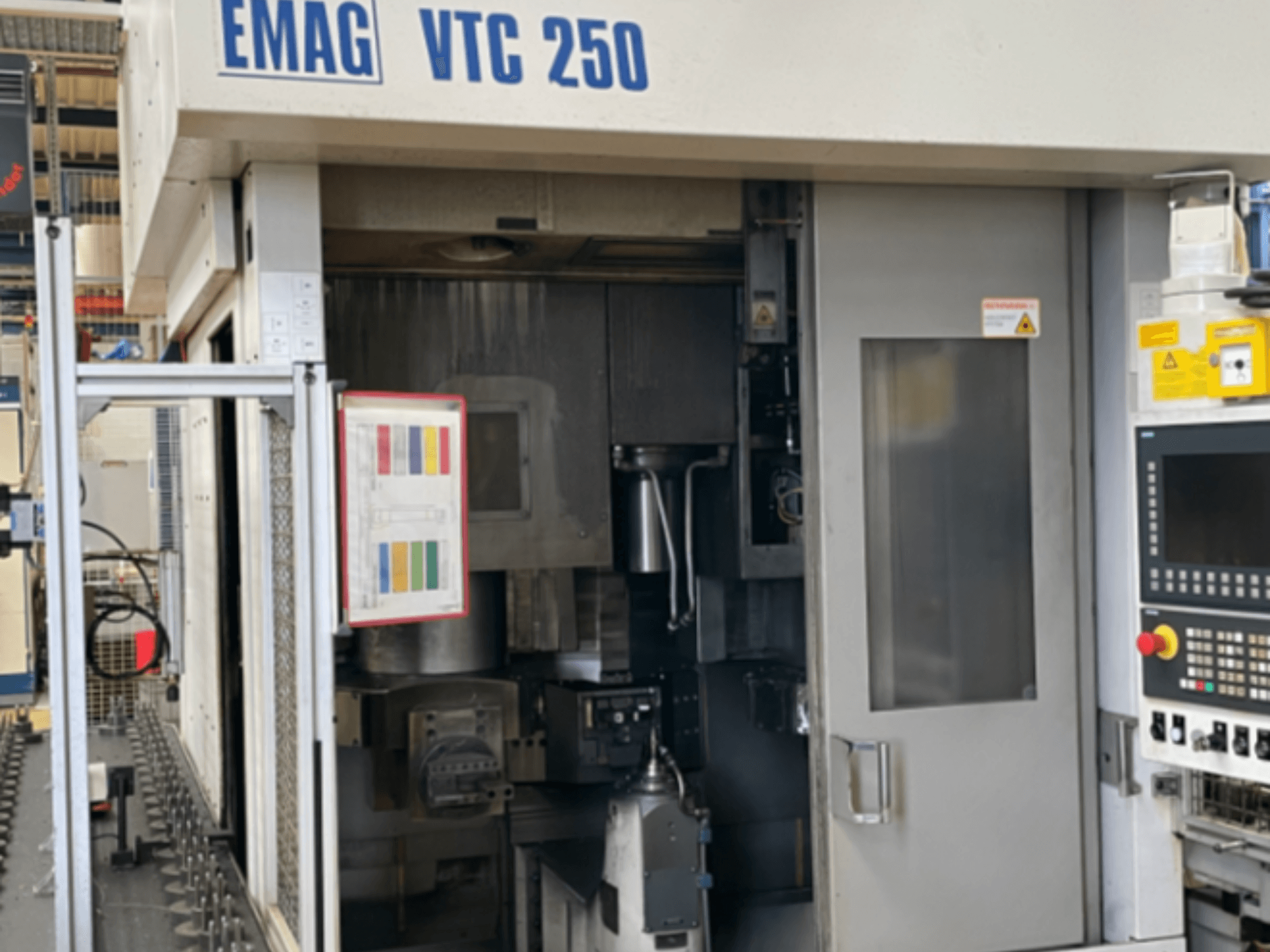 Vooraanzicht van de EMAG VTC 250 verticale draaimachine, met het bedieningspaneel, de bedieningsinterface en de geopende toegangsdeur.
