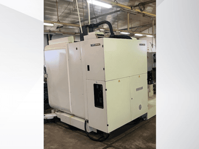 Witte industriële CNC machine gezien vanaf de voorkant, met bedieningspaneel en ventilatie, in een werkplaats.