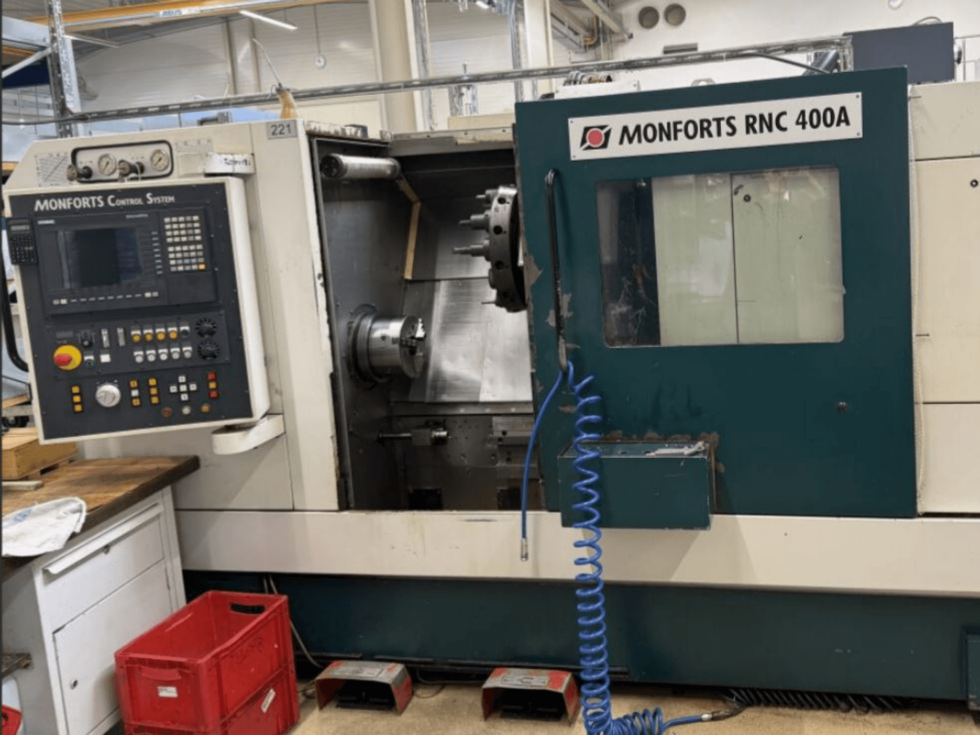 Monforts RNC 400 A horizontale draaimachine, vooraanzicht, met het bedieningspaneel en het werkgebied met gemarkeerde functies.