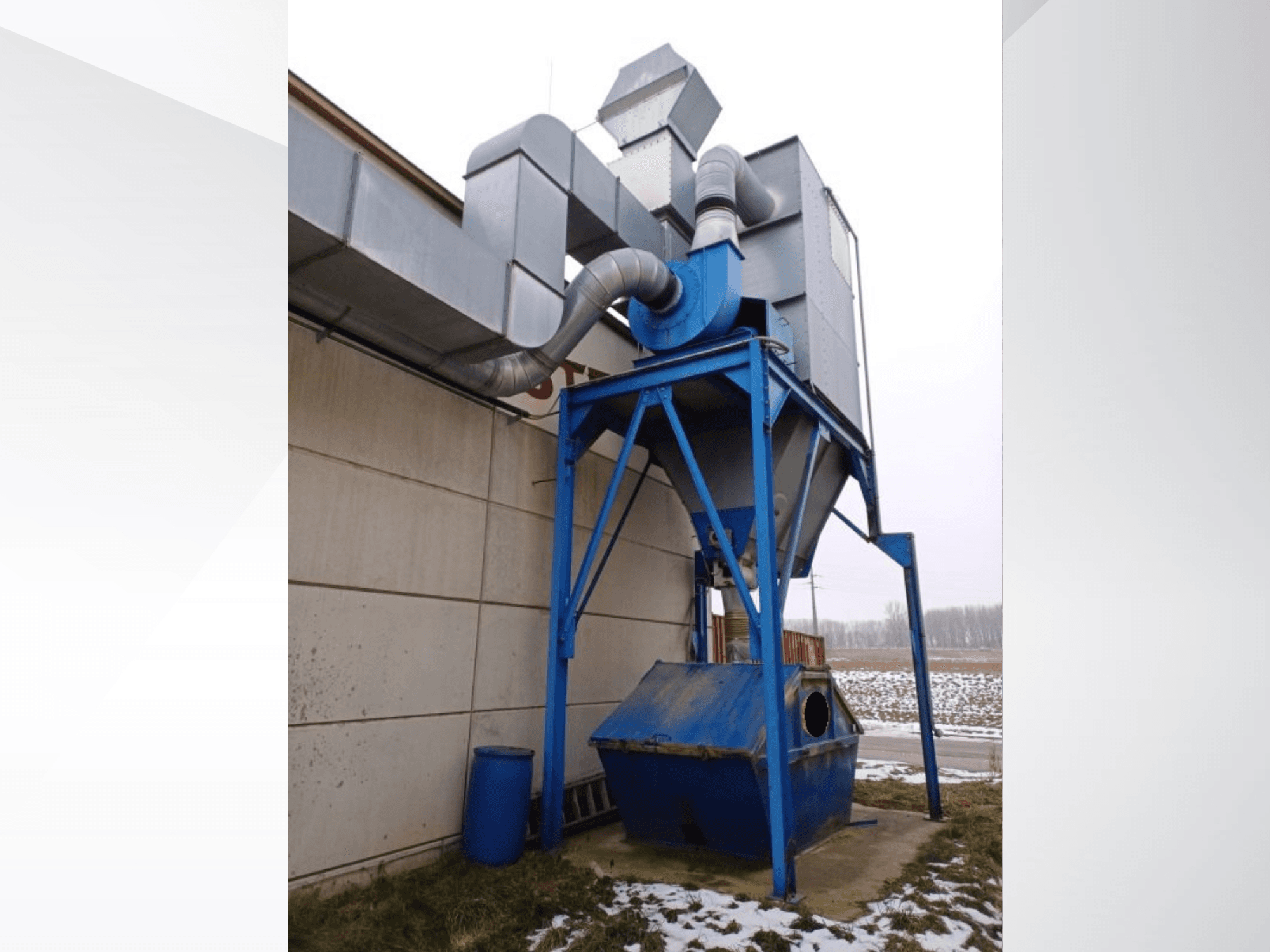 LBH afzuigsysteem in blauw met een cilindrische afscheider en verbindingsbuizen, vooraanzicht tegen een besneeuwde achtergrond.