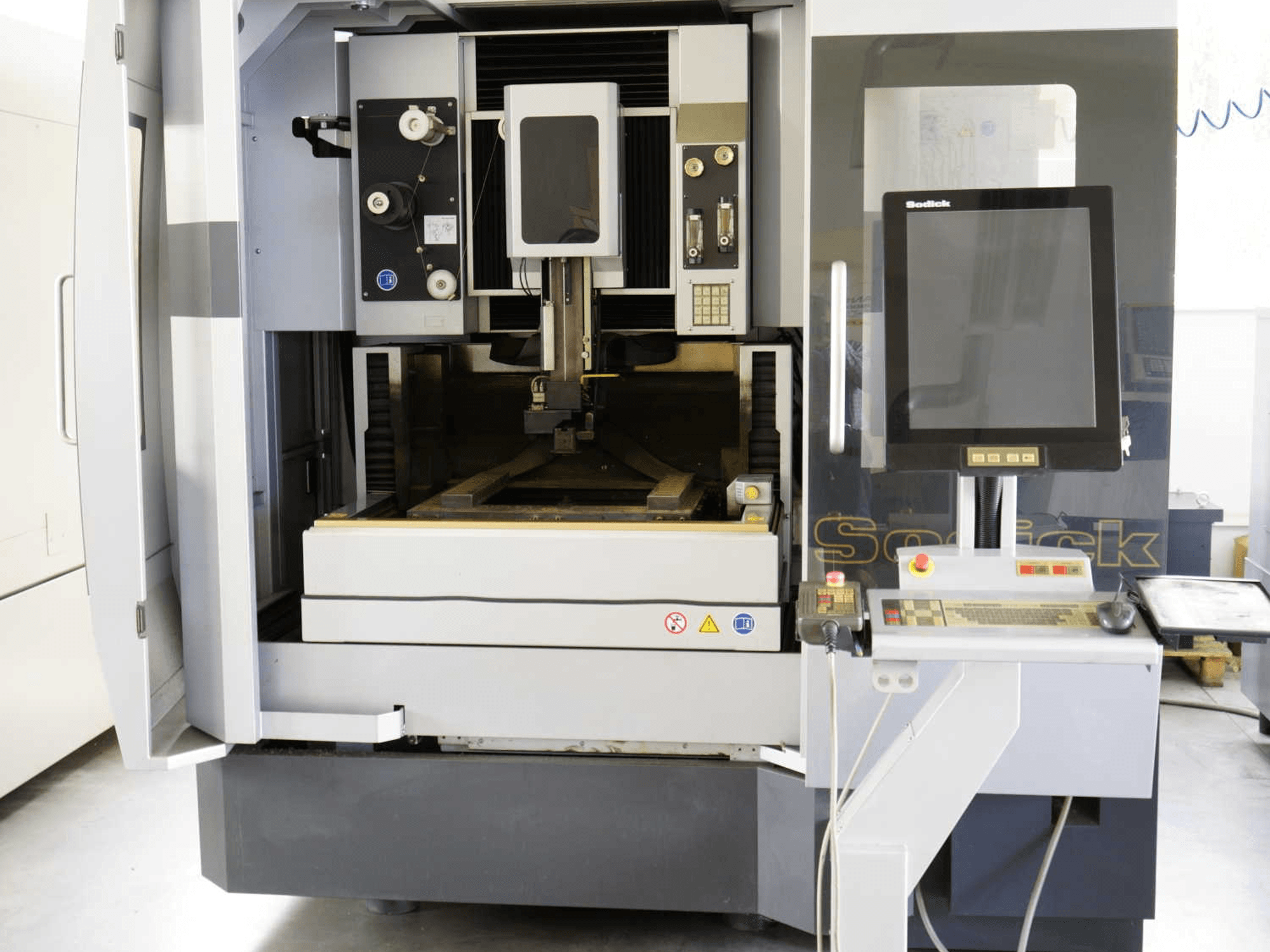 Vooraanzicht van de Sodick SLC400G draadvonkmachine, waarbij het bedieningspaneel, het werkgebied en de interne mechanismen duidelijk zichtbaar zijn.