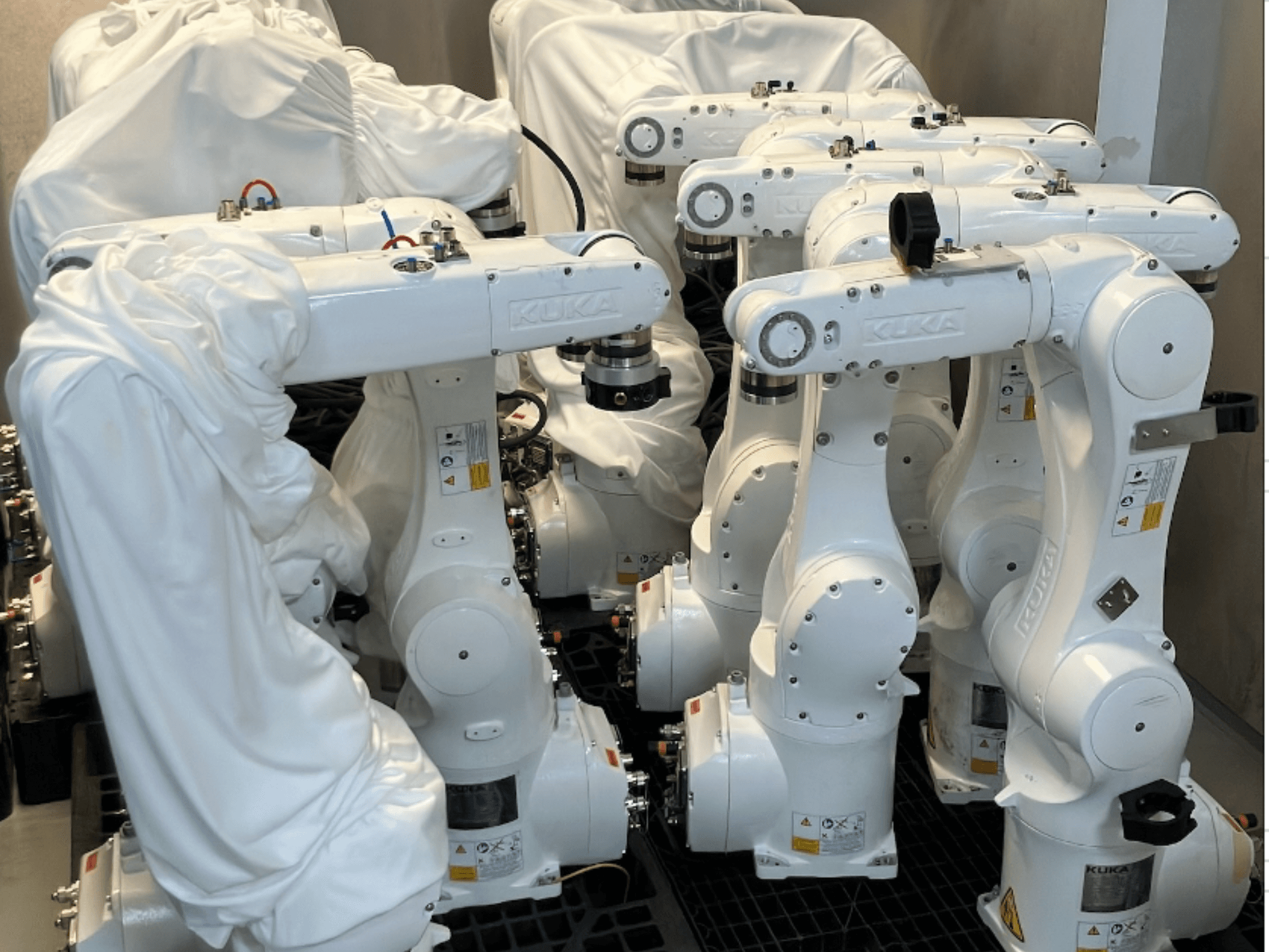 KUKA KR 10 R900-2 robotarmen bekleed met witte stof, bovenaanzicht, met meerdere eenheden in opslag.