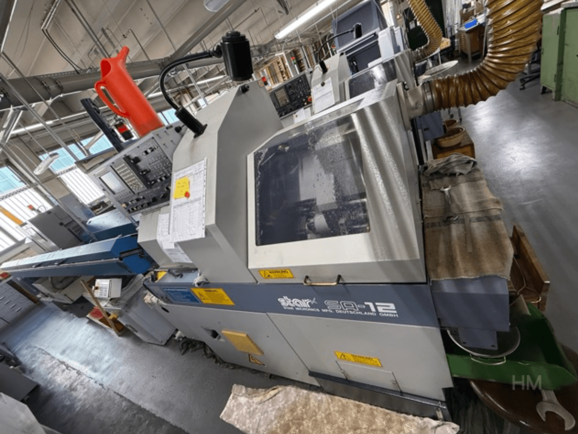 Star SQ-12 bewerkingscentrum, zijaanzicht met bedieningspaneel, koelvloeistofreservoir en stofafzuigslang zichtbaar.