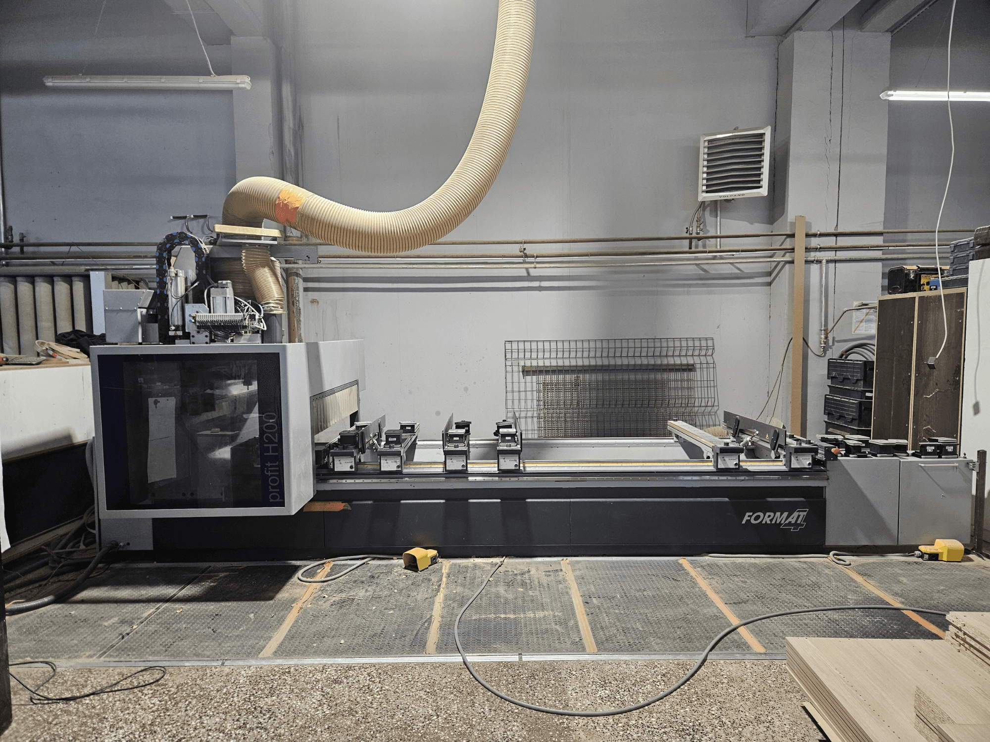 Een FORMAT profit H200 CNC machine in een werkplaats, zijaanzicht, met het werkoppervlak en het stofafzuigsysteem.