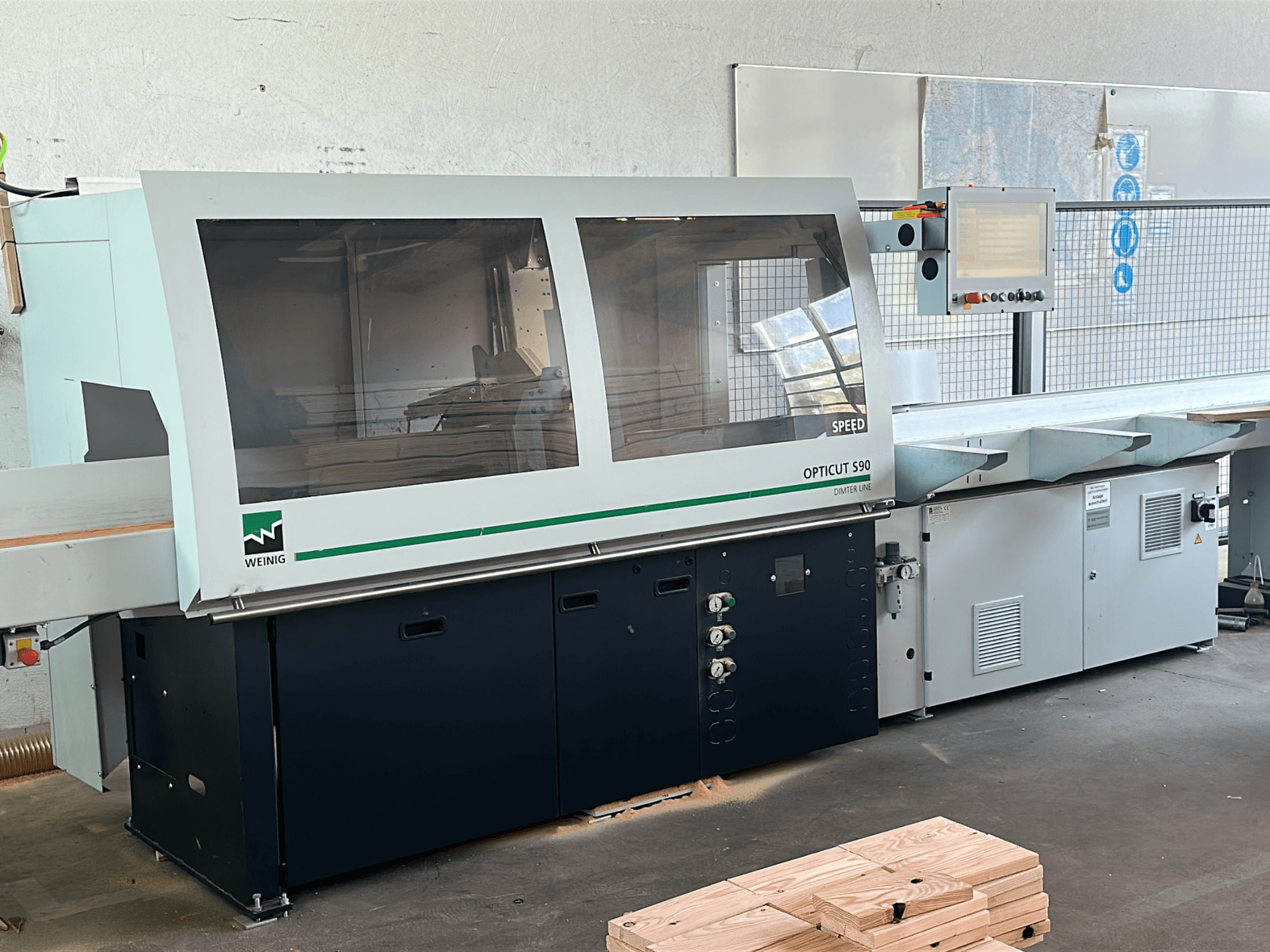 WEINIG Opticut S90 optimaliserende afkortzaag in vooraanzicht, met een duidelijke veiligheidsbehuizing en bedieningspaneel.