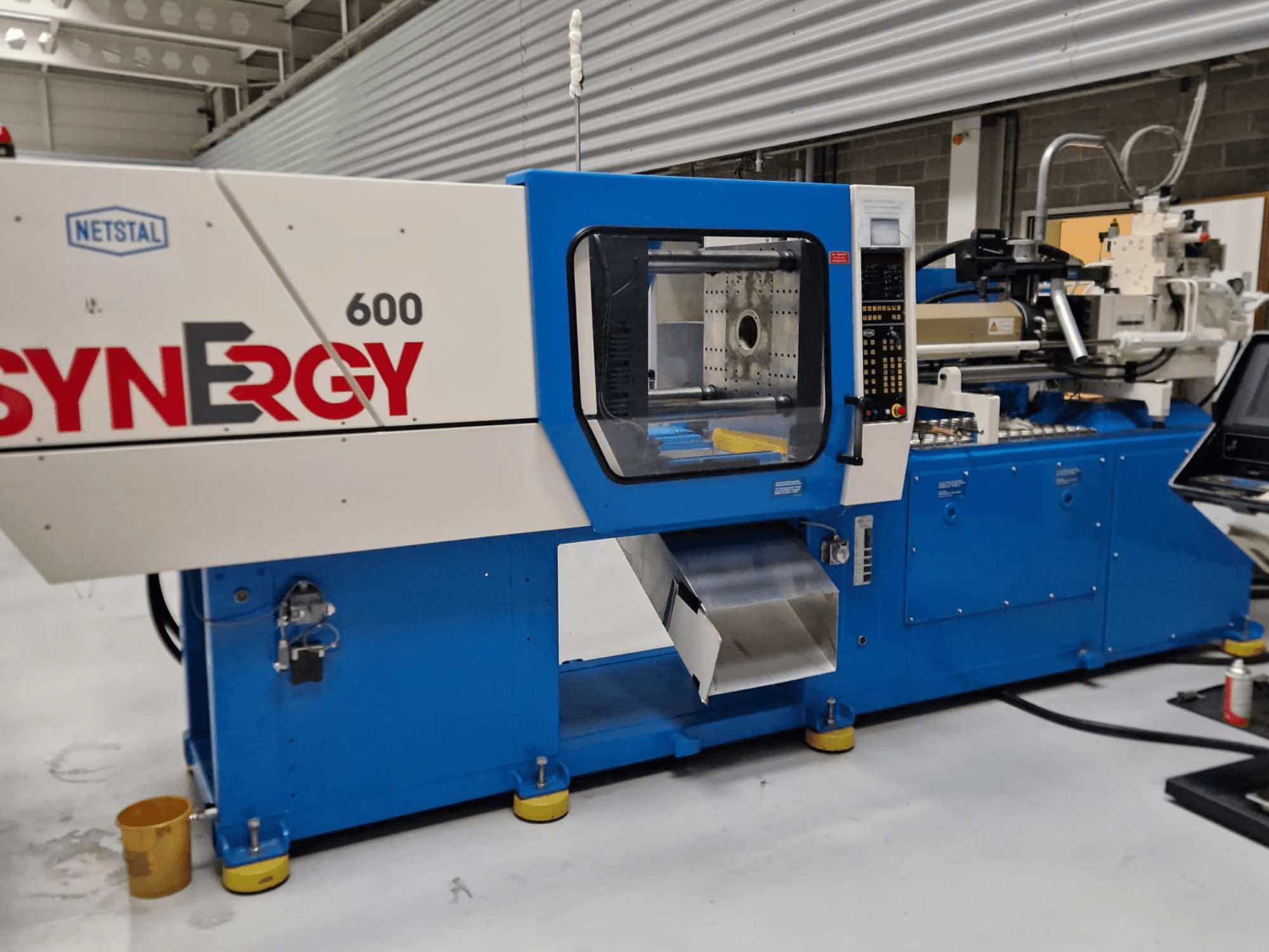 Netstal Synergy 600-230 hydraulische spuitgietmachine, zijaanzicht met bedieningspaneel en inspuitgedeelte.