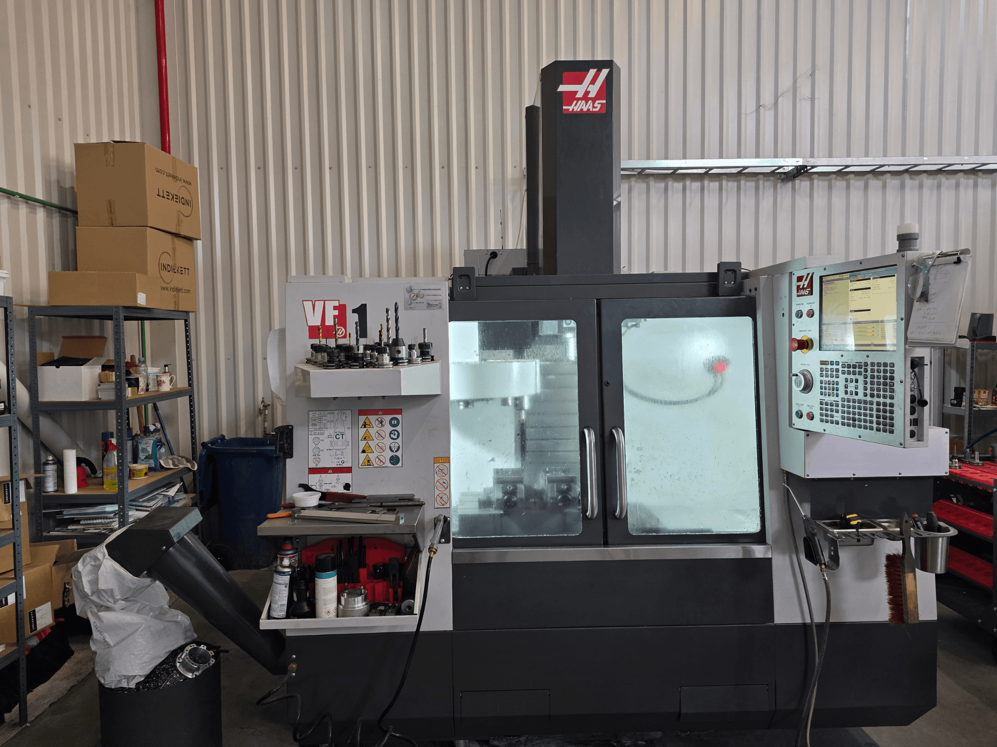 HAAS VF 1 verticaal bewerkingscentrum in een werkplaats, vooraanzicht met bedieningspaneel en freesgedeelte met gereedschappen.