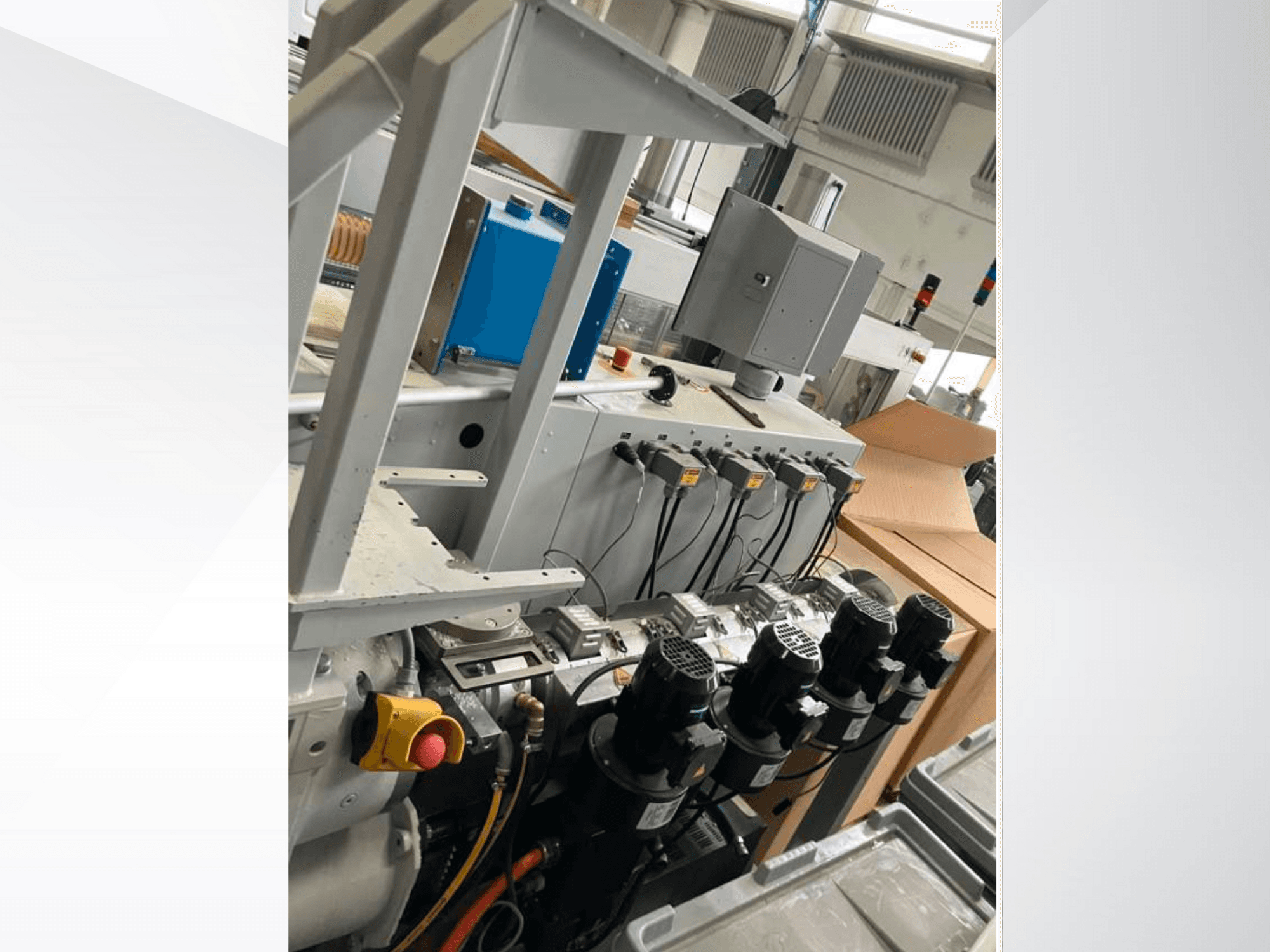 Bedieningspaneel voor industriële machines met meerdere motoren, meters en een monitor; zijaanzicht in een fabrieksomgeving.