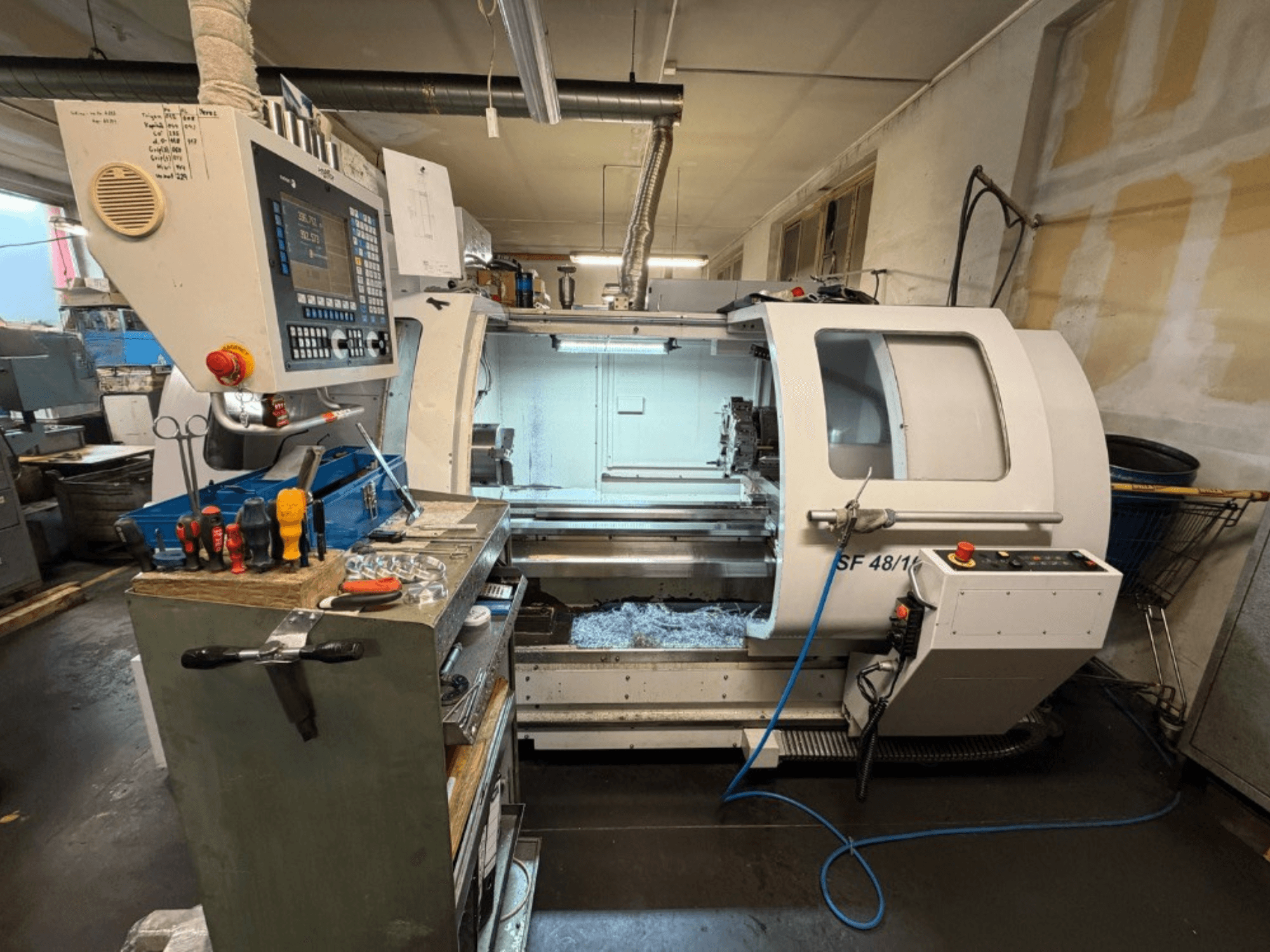 Horizontale draaimachine MICROCUT SF 48/1000 gezien vanaf de voorkant, met een bedieningspaneel en gereedschappen op de werkbank.