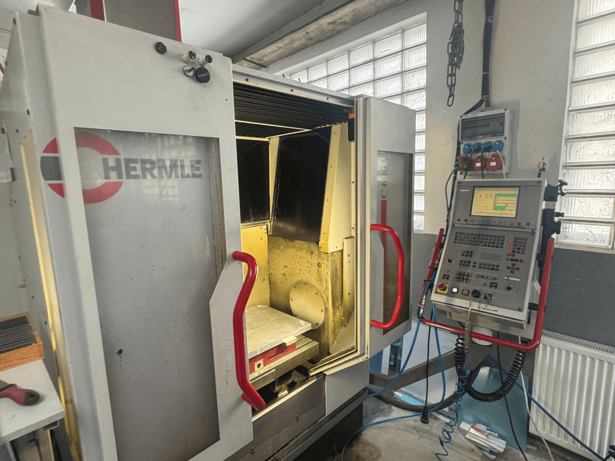 HERMLE C600V verticaal bewerkingscentrum, vooraanzicht met open deur, bedieningspaneel en binnenwerkgebied.