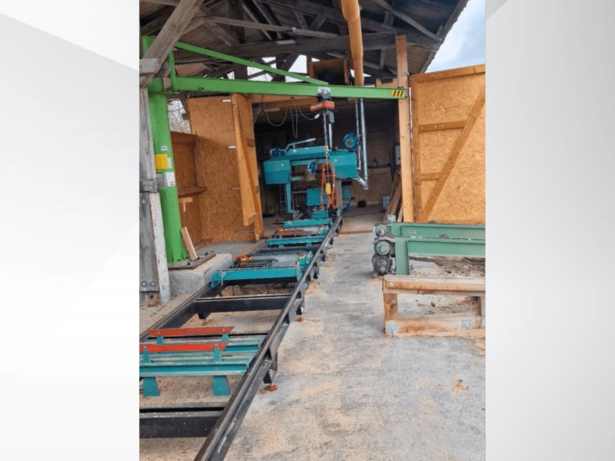 Horizontale lintzaagmachine in werkplaats, gezien vanaf de voorkant. De uitrusting omvat een rupsband en extra groene accessoires.