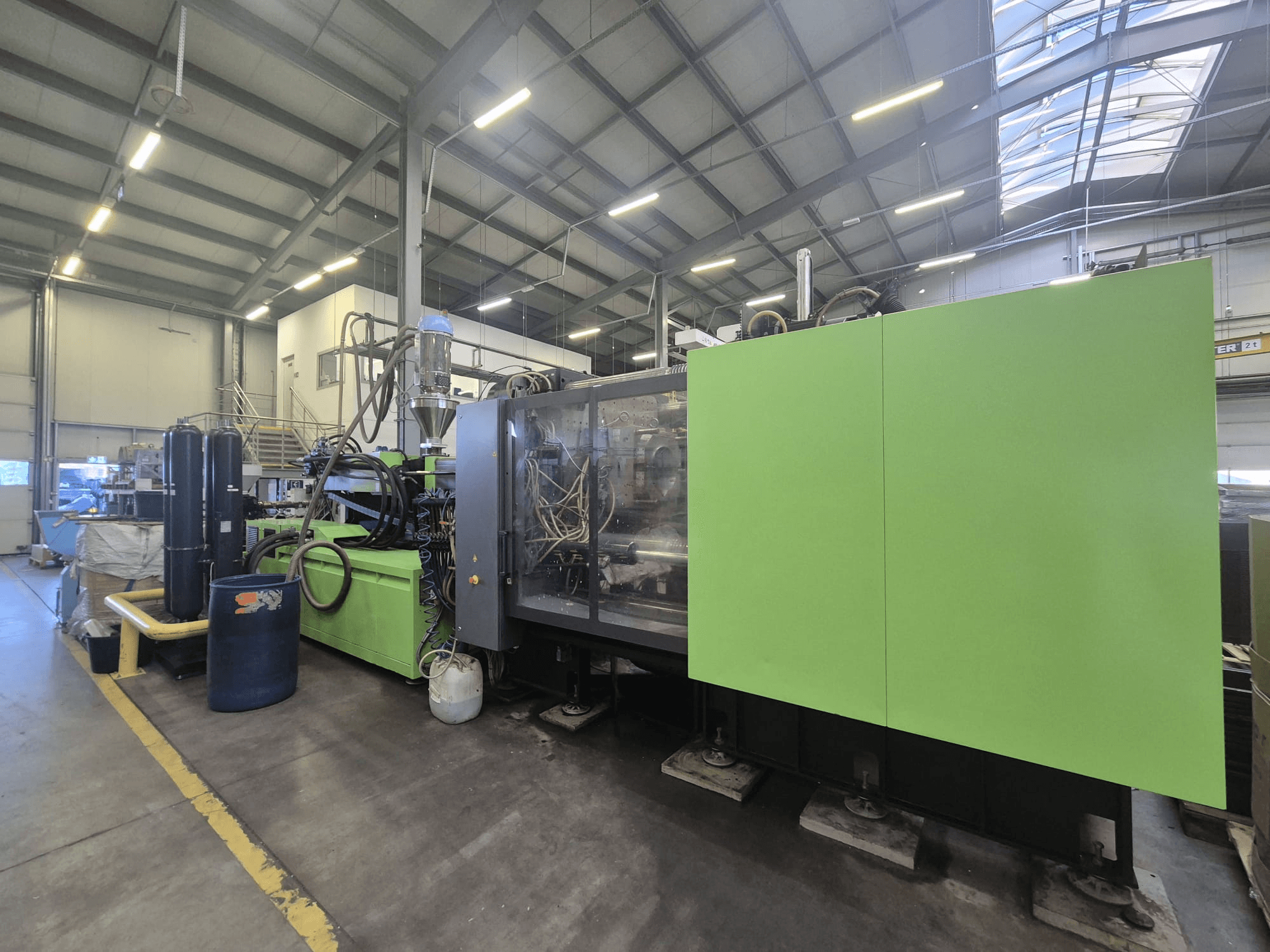 Een hydraulische spuitgietmachine van het type Engel Duo 5160/700 in een fabrieksomgeving, gezien vanaf de zijkant, waarbij de groene behuizing en de onderdelen goed te zien zijn.