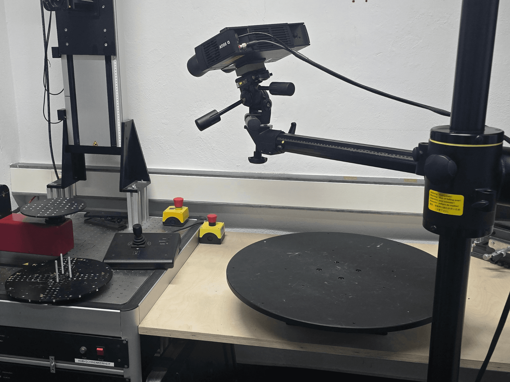 Vooraanzicht van de optische meetmachine ZEISS ATOS Q 12M, met een scankop, bedieningspaneel en een draaiend cirkelvormig platform.