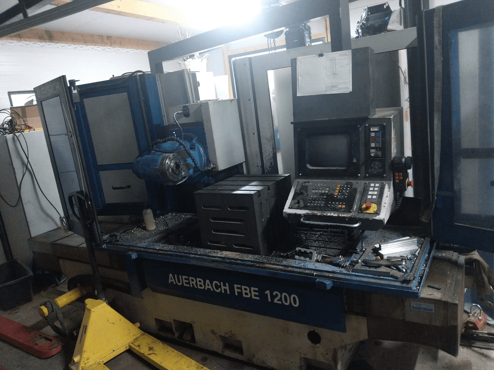 Auerbach FBE 1200 metaalboormachine, vooraanzicht, met het bedieningspaneel, de motor en metaalschilfers op het werkoppervlak.